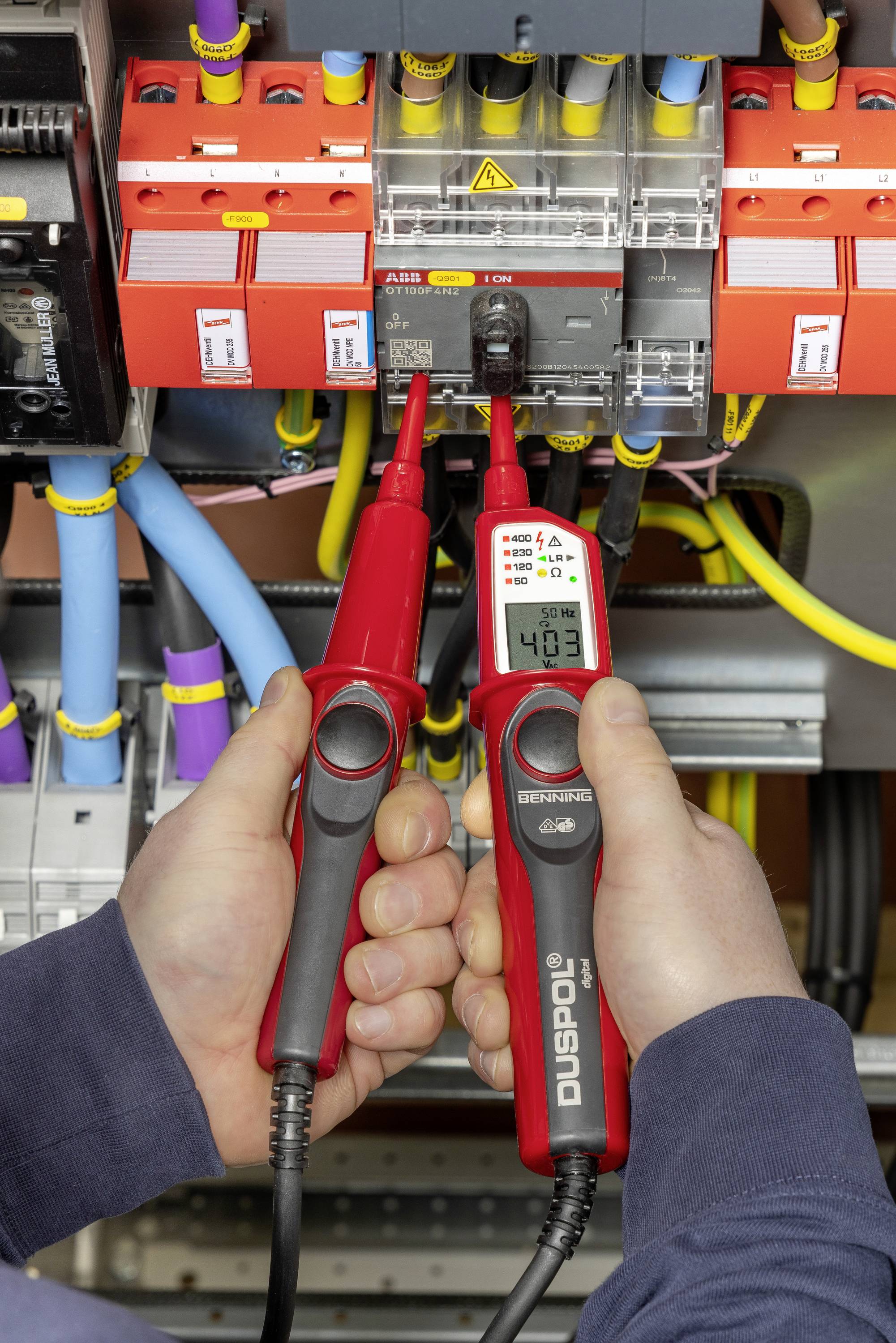 Ein Techniker misst mit einem Spannungsprüfer 403 Volt an einem elektrischen Schaltschrank.