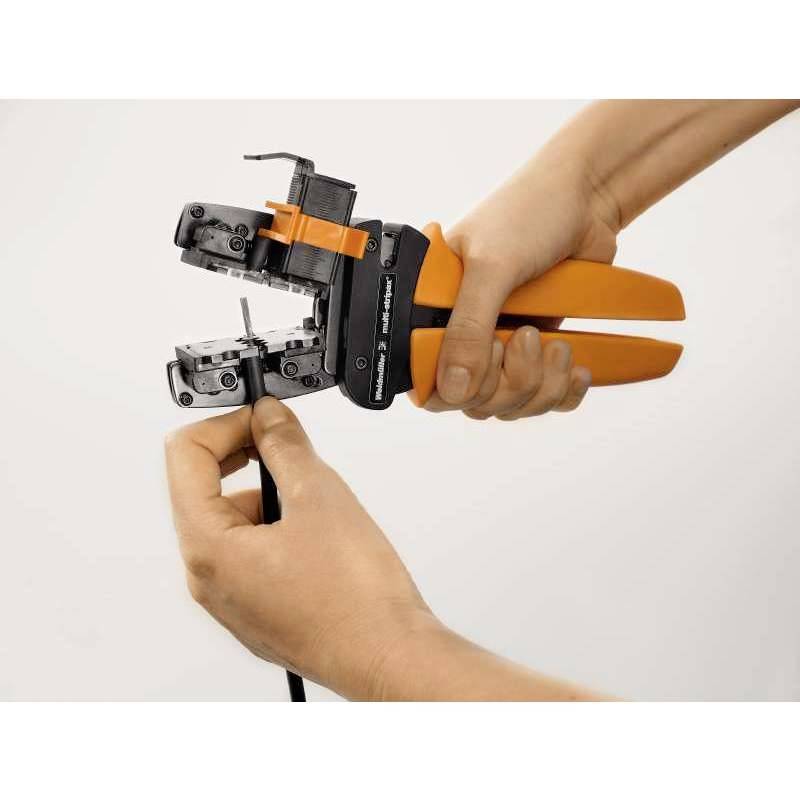 Eine Person benutzt eine orangefarbene Crimpzange, um ein Kabelanschluss zu befestigen. Hände halten die Zange und das Kabel.