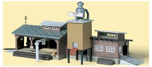 Maßstabsmodell eines Industriegebäudekomplexes mit einem hohen zentralen Turm, Lagerhalle und Laderampe, gezeigt vor einem einfachen Hintergrund.