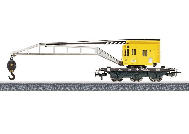 Ein Modellbahn-Kranwagen mit einer gelben Kabine und einem ausgefahrenen Arm mit schwarzem Haken, auf einer Spur positioniert, verwendet für Modelleisenbahn-Anlagen.