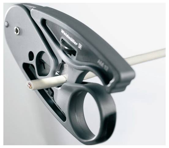 Eine Nahaufnahme eines Abisolationswerkzeugs, das die Isolierung von einem Draht abschneidet, wobei die Klinge in Kontakt mit dem Draht steht.