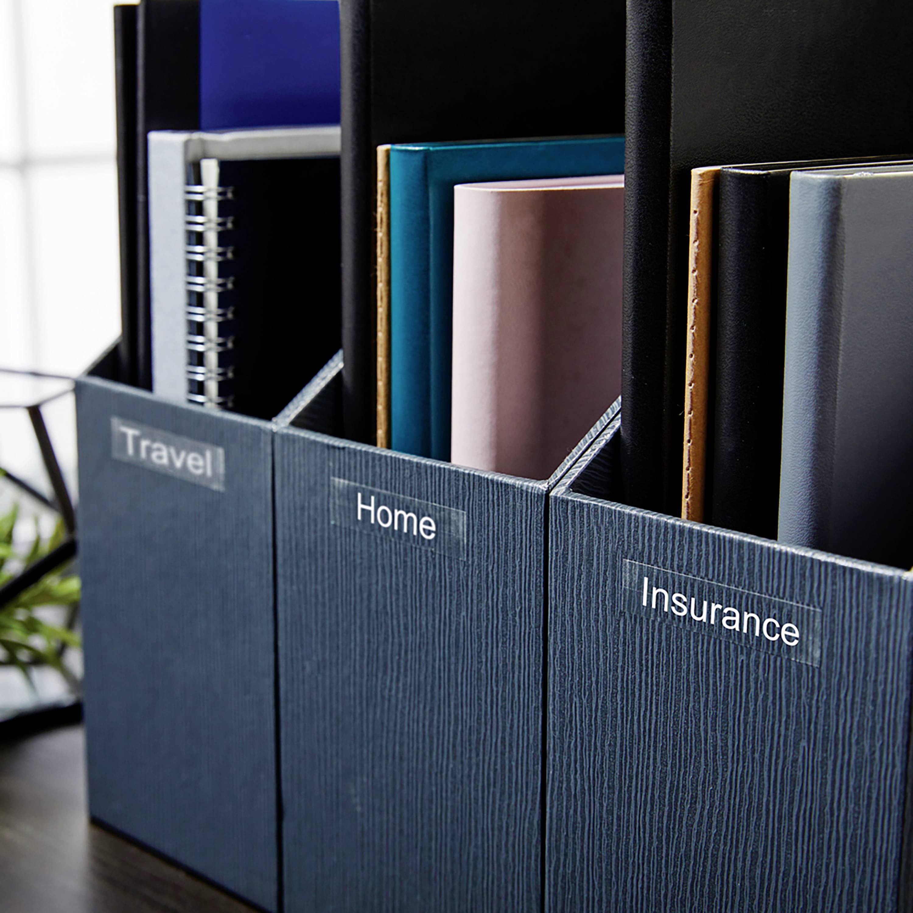 Drei Aktenordner in einem Regal sind mit 'Travel', 'Home' und 'Insurance' beschriftet, was auf eine organisierte Ablage hinweist.