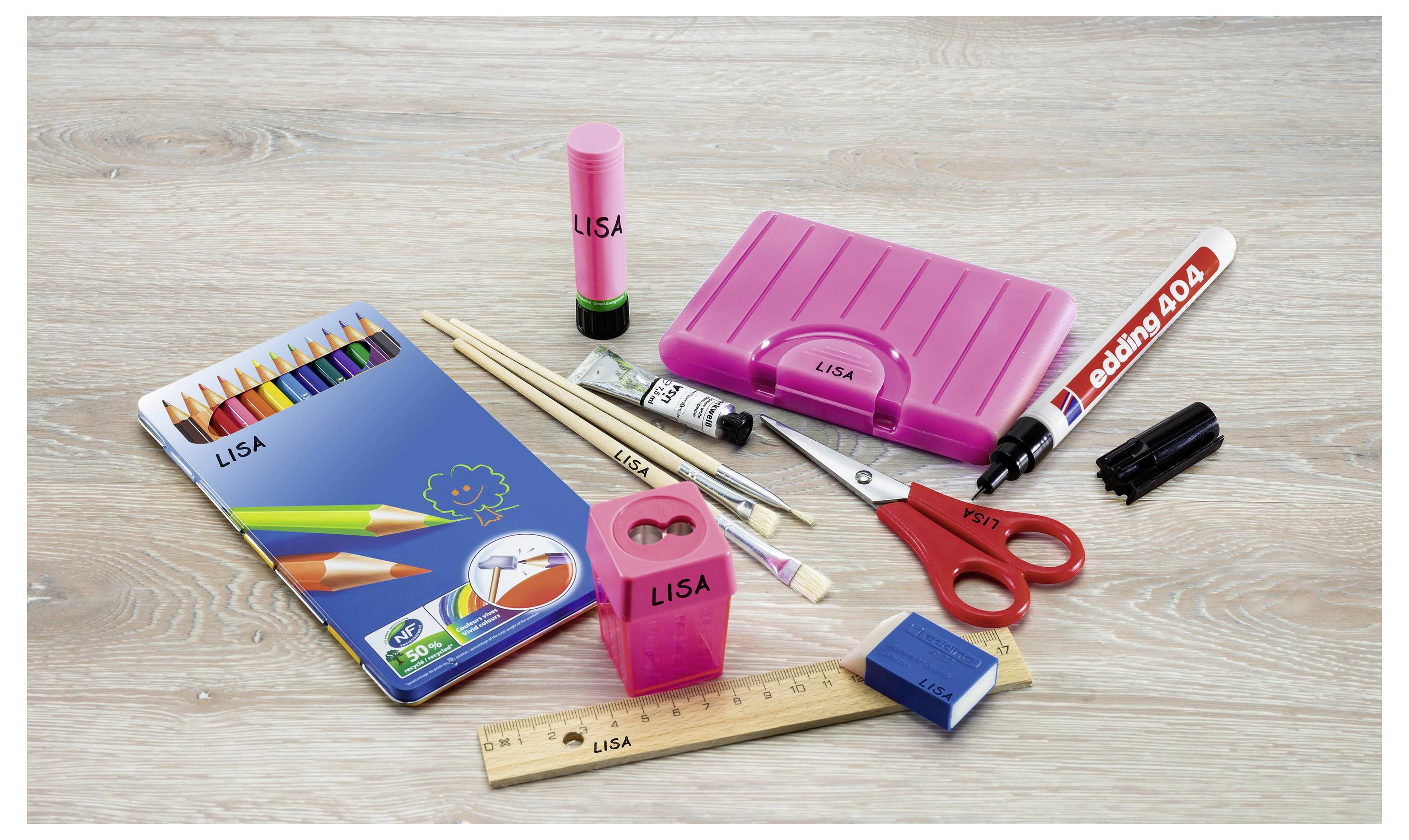 Sortierte rosa Schulmaterialien auf einem Holztisch, darunter ein Federmäppchen, ein Notizbuch, eine Schere, ein Lineal, einen Marker, einen Bleistiftspitzer und Stifte, mehrere mit der Aufschrift "LISA" beschriftet.
