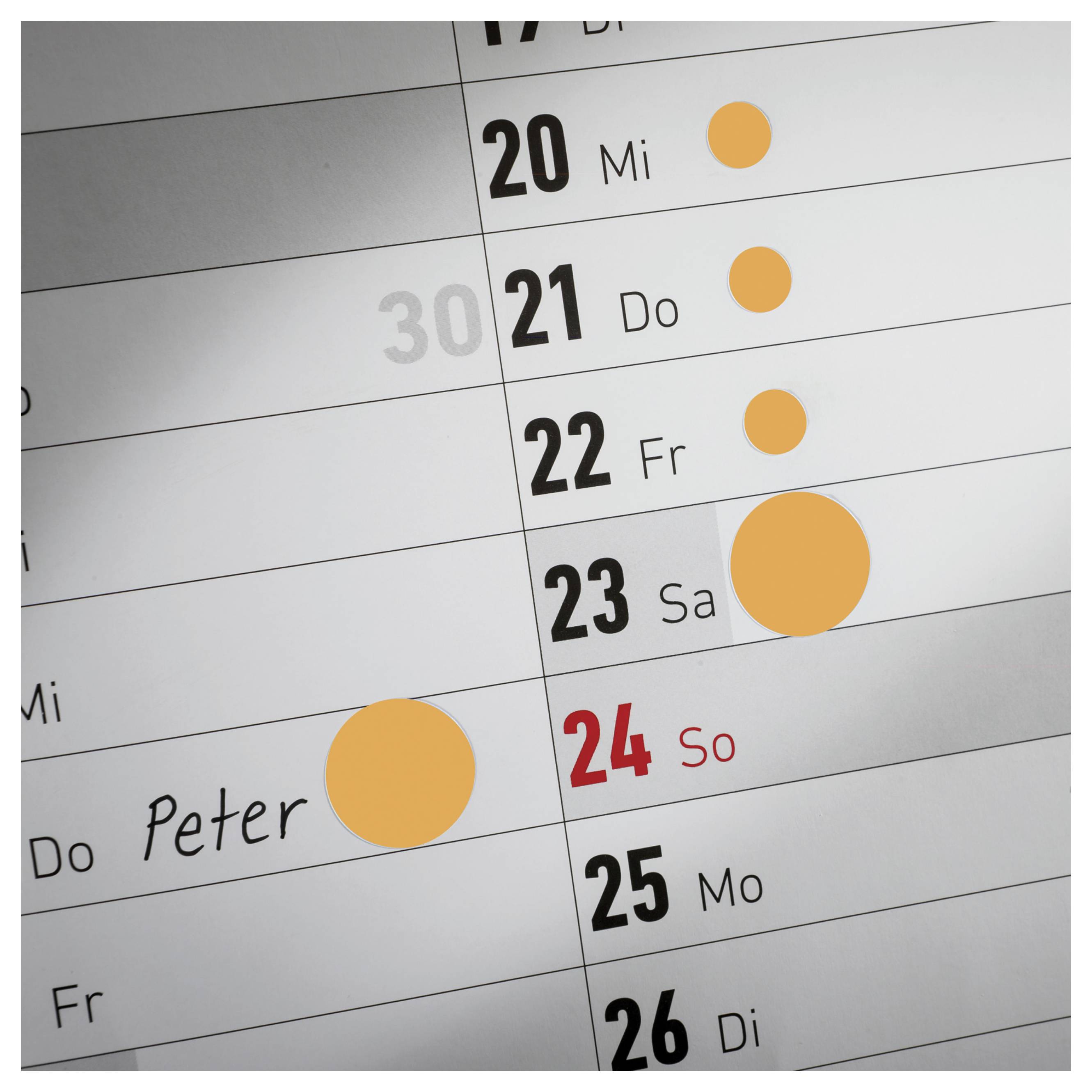 Kalenderansicht mit markierten Terminen an mehreren Tagen; ein Eintrag 'Peter' am 23. und farbige Kreise als Ereignisse neben 20–24.