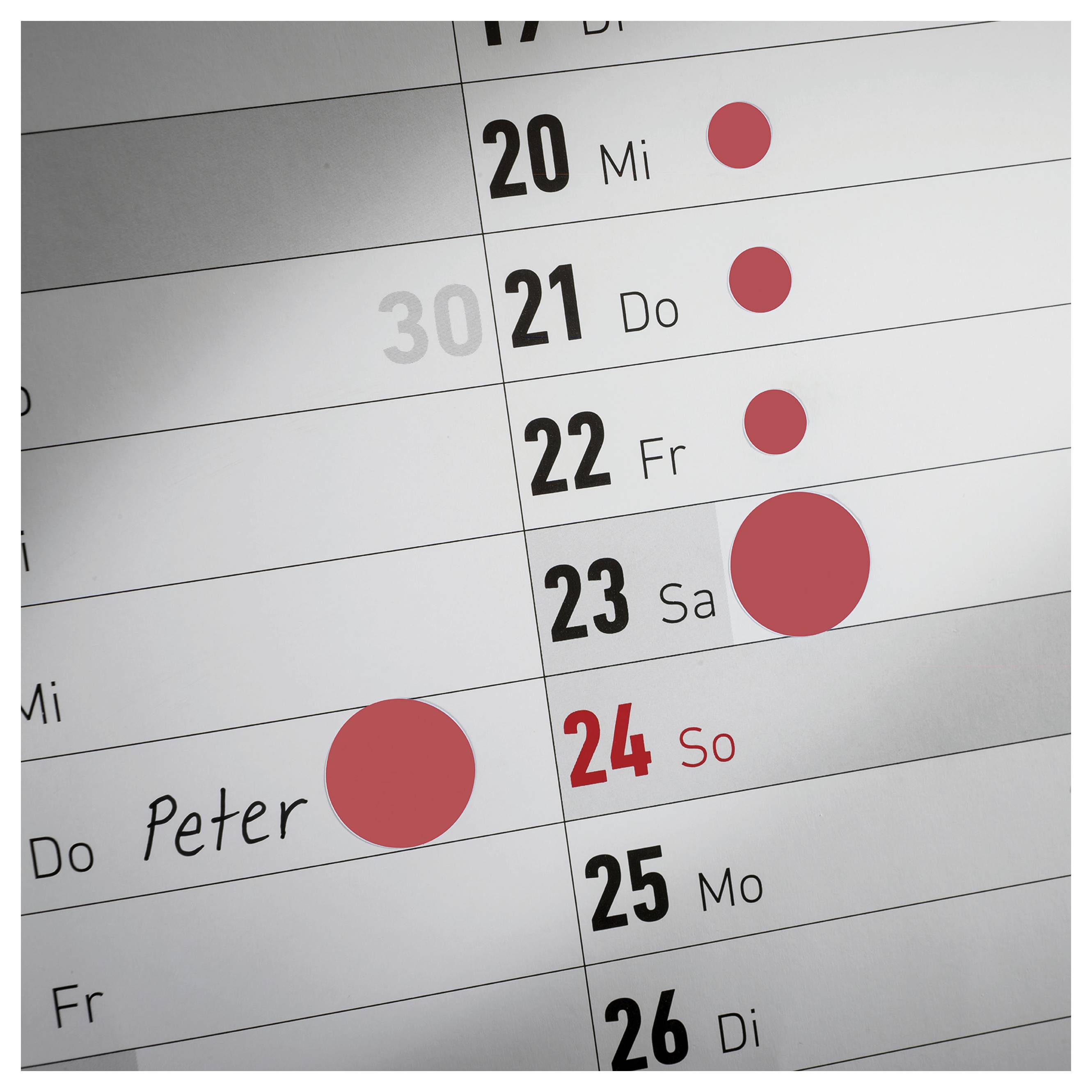 Nahaufnahme eines Kalenders mit den Tagen 20 bis 26; rote Punkte markieren Termine, ein Termin ist bei 24 So als 'Peter' eingetragen.