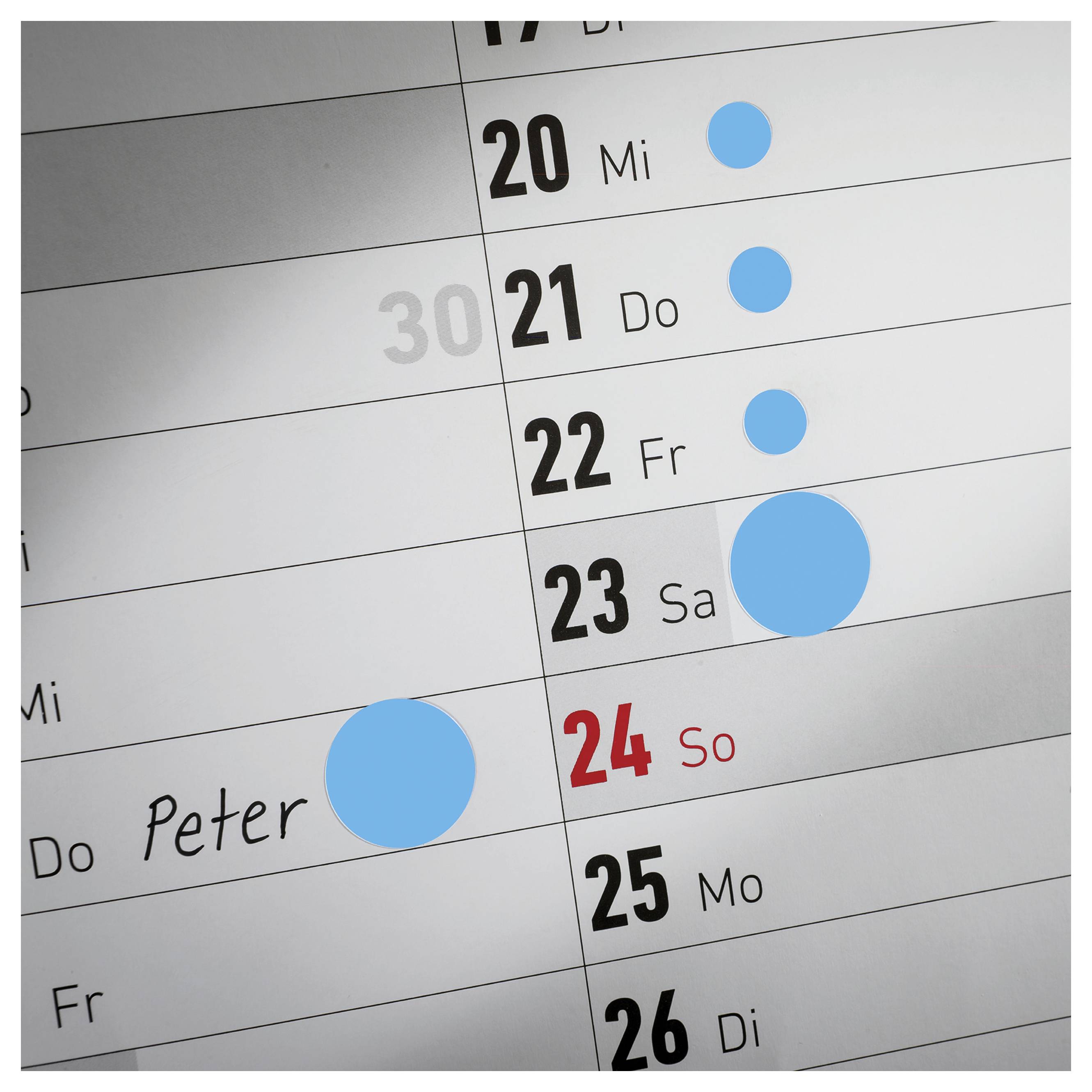Nahaufnahme eines Kalenderplans mit den Daten 20 bis 26; blaue Markierungen heben Termine hervor, 'Peter' ist am 24. So eingetragen.