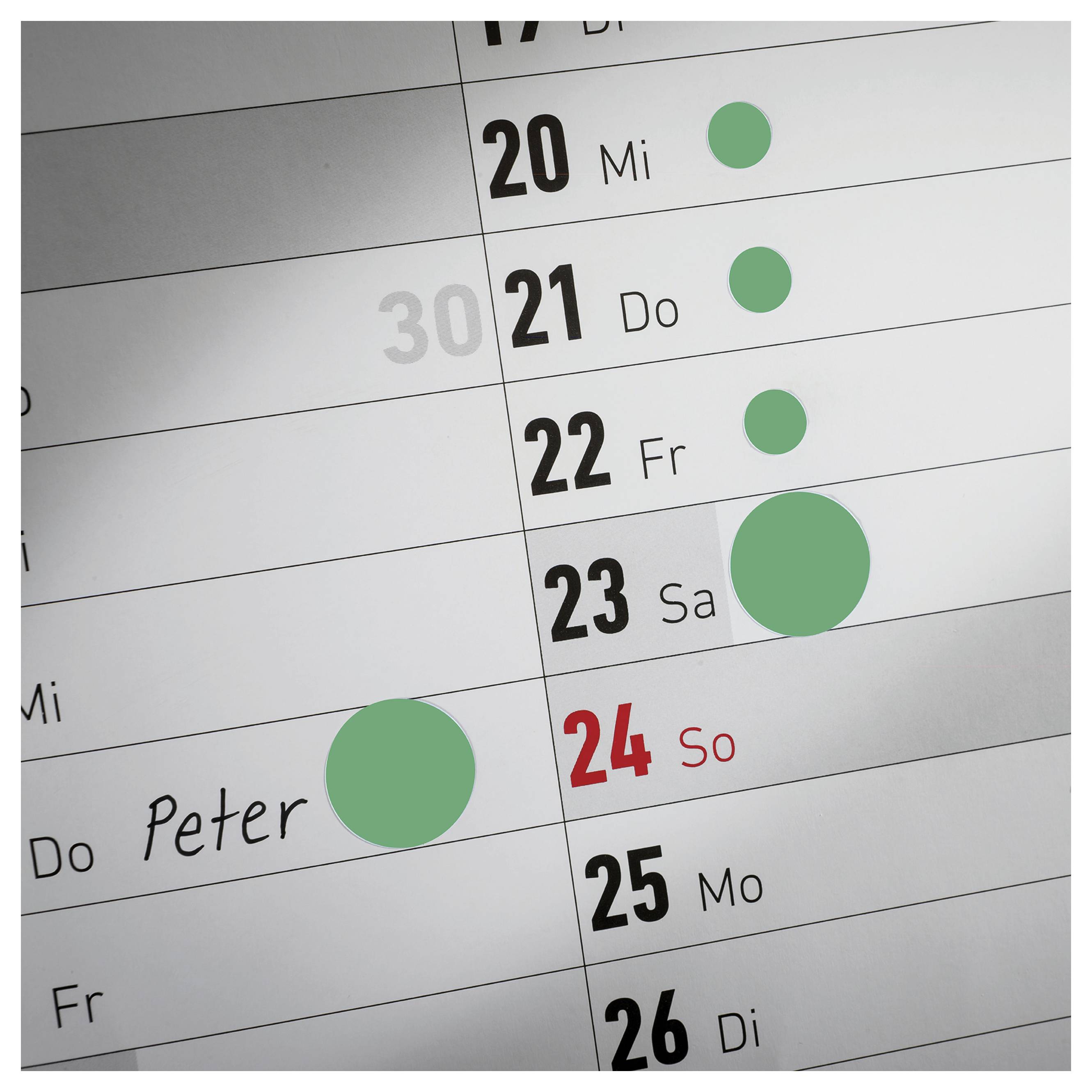 Nahaufnahme eines Terminplans mit dem Namen 'Peter'; mehrere grüne Markierungen auf den Tagen 20 bis 23 und 24. Sonntag ist rot hervorgehoben.