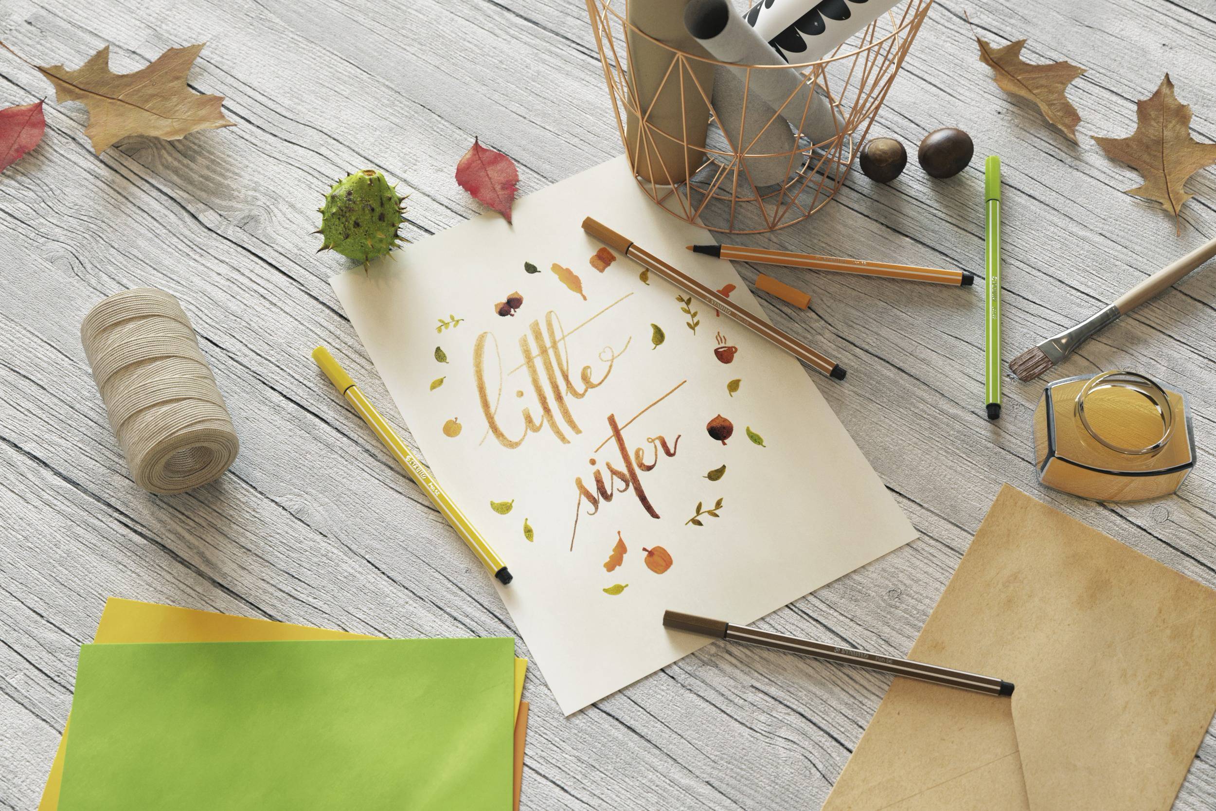 Papier mit handgeschriebenem Text 'little mister' umgeben von Blättern und Stiften auf einem Tisch, herbstliches Thema.