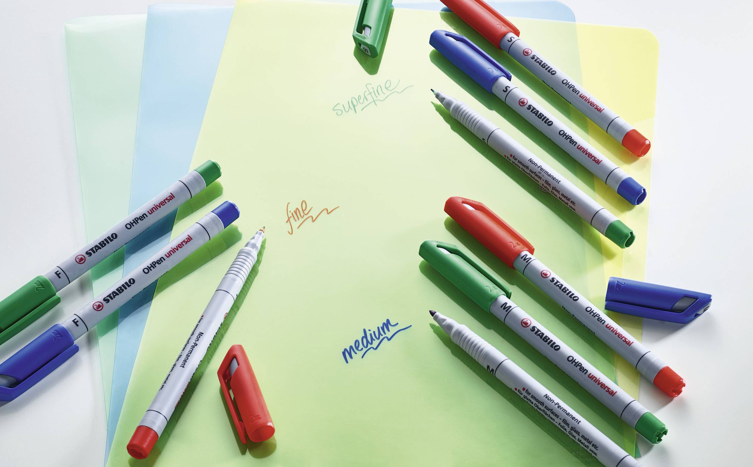 Stifte verschiedener Farben und Stärken liegen auf bunten Blättern. Notizen beschreiben Farben und Strichstärken: 'sunshine', 'fine', 'medium'.