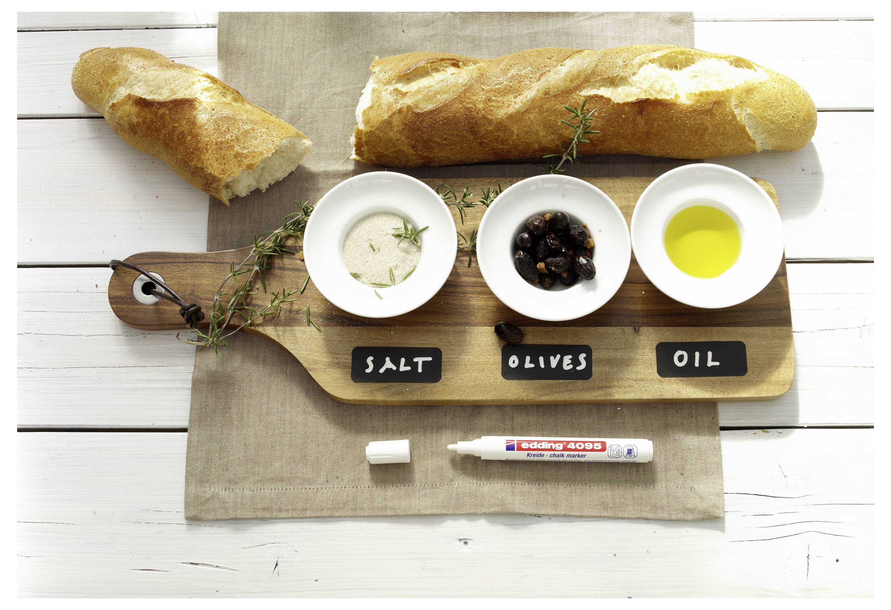 Zwei Baguettes auf einem Holzbrett mit Schüsseln mit Salz, Oliven und Olivenöl mit den Beschriftungen „SALT", „OLIVES" und „OIL" sowie einem Marker.