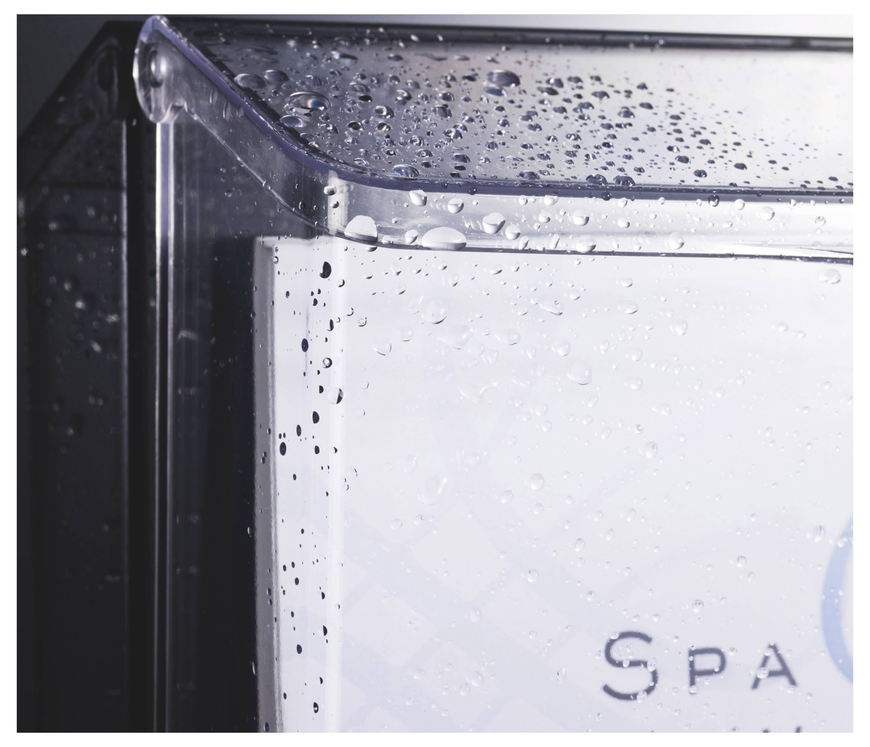 Nahaufnahme eines durchsichtigen Kunststoffbehälters mit Wassertropfen auf dem Deckel und der Seite, wobei das Wort „SPA" teilweise auf der Vorderseite sichtbar ist.