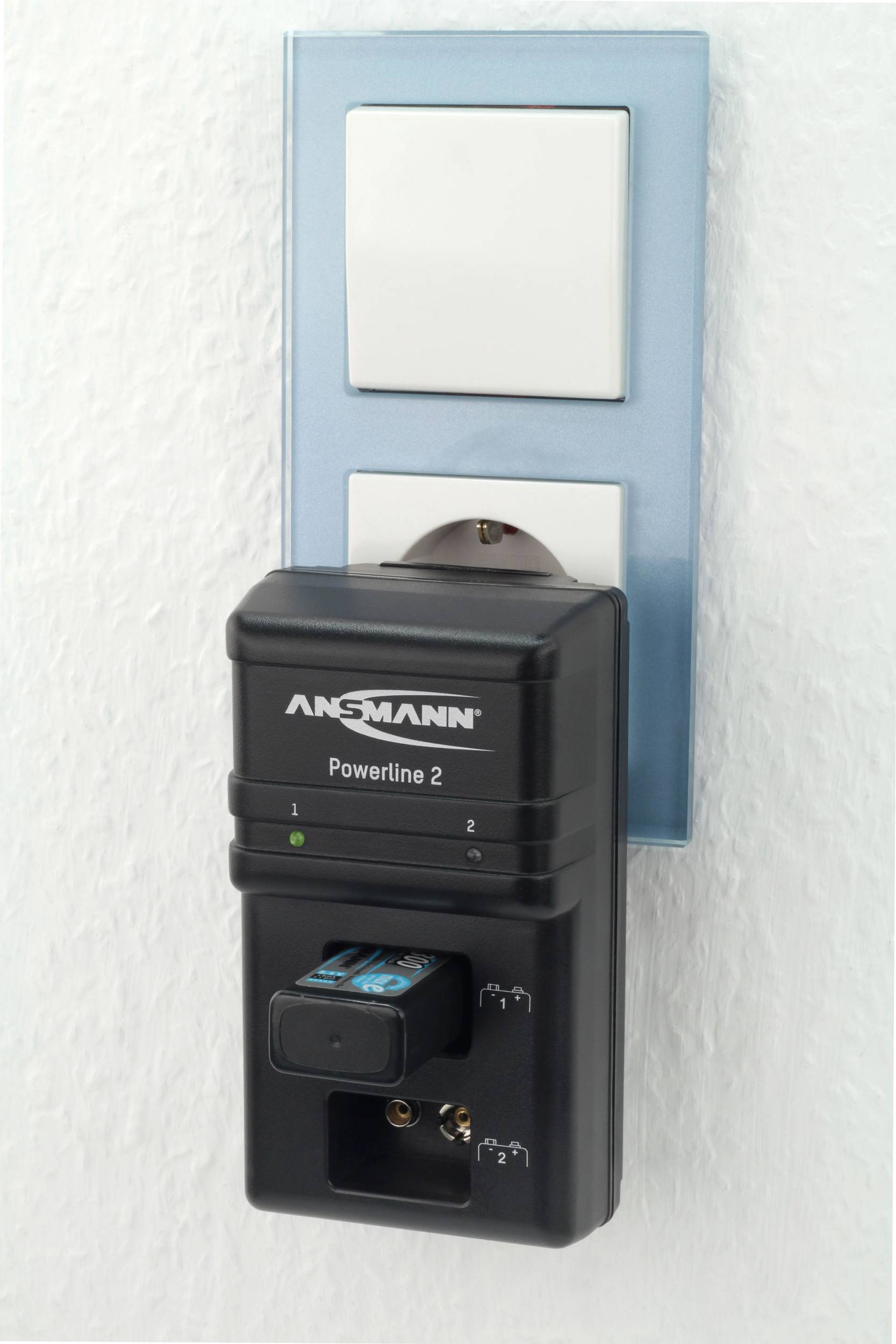Ein Ladegerät 'Ansmann Powerline 2' steckt in einer Steckdose und lädt zwei AA-Batterien.
