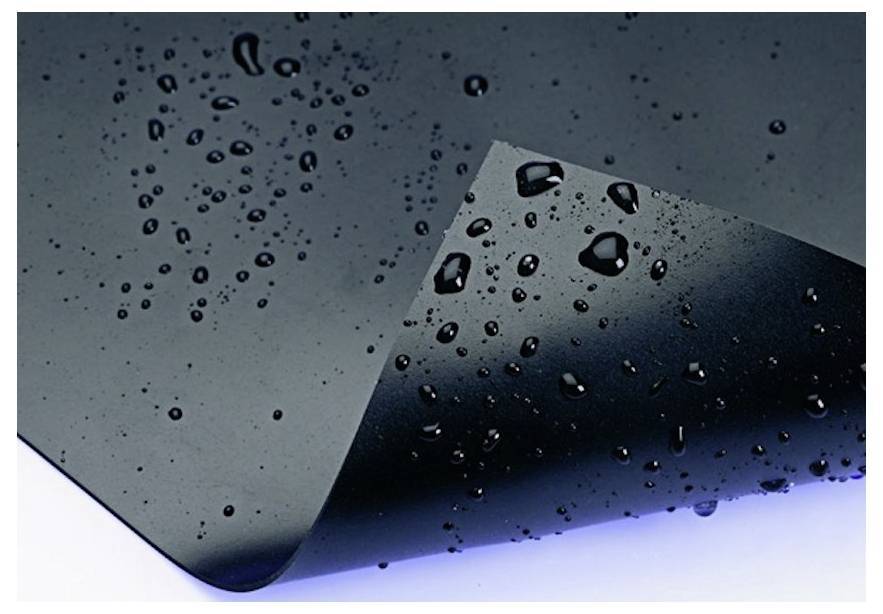 Nahaufnahme einer glänzend schwarzen Oberfläche mit Wassertropfen, die eine gefaltete oder gekrümmte Kante gegen einen hellen Hintergrund zeigt.