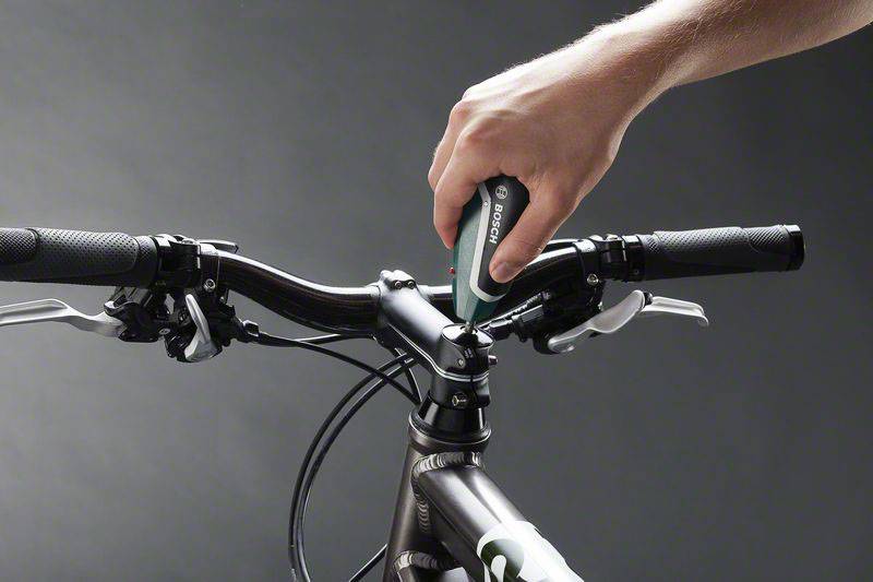 Eine Hand zieht mit einem Elektroschrauber die Schraube am Vorbau eines Fahrradlenkers fest.