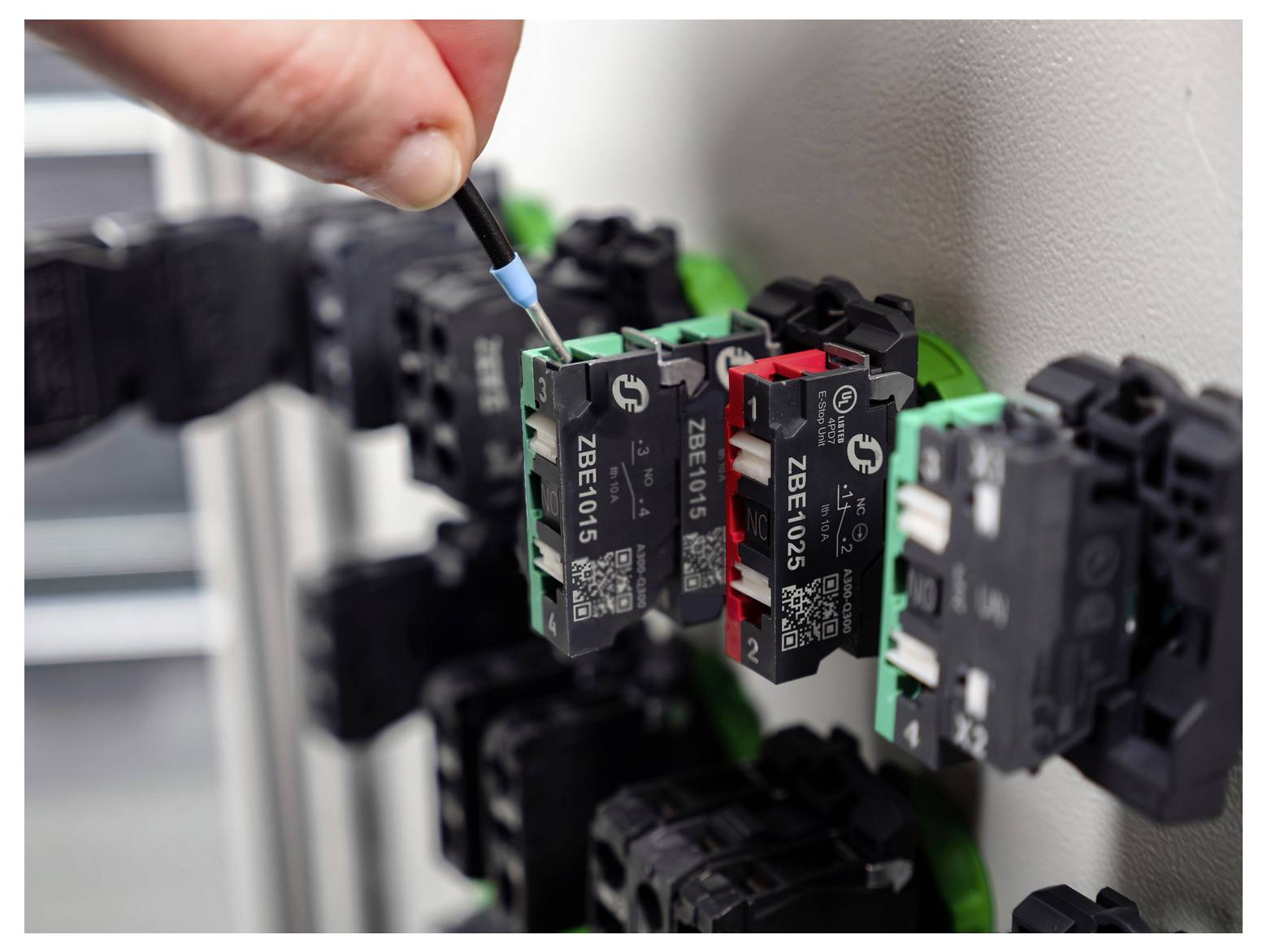 Eine Hand benutzt einen Schraubendreher, um ein Modul einer Elektrosteuertafel mit beschrifteten Schaltungskomponenten einzustellen.