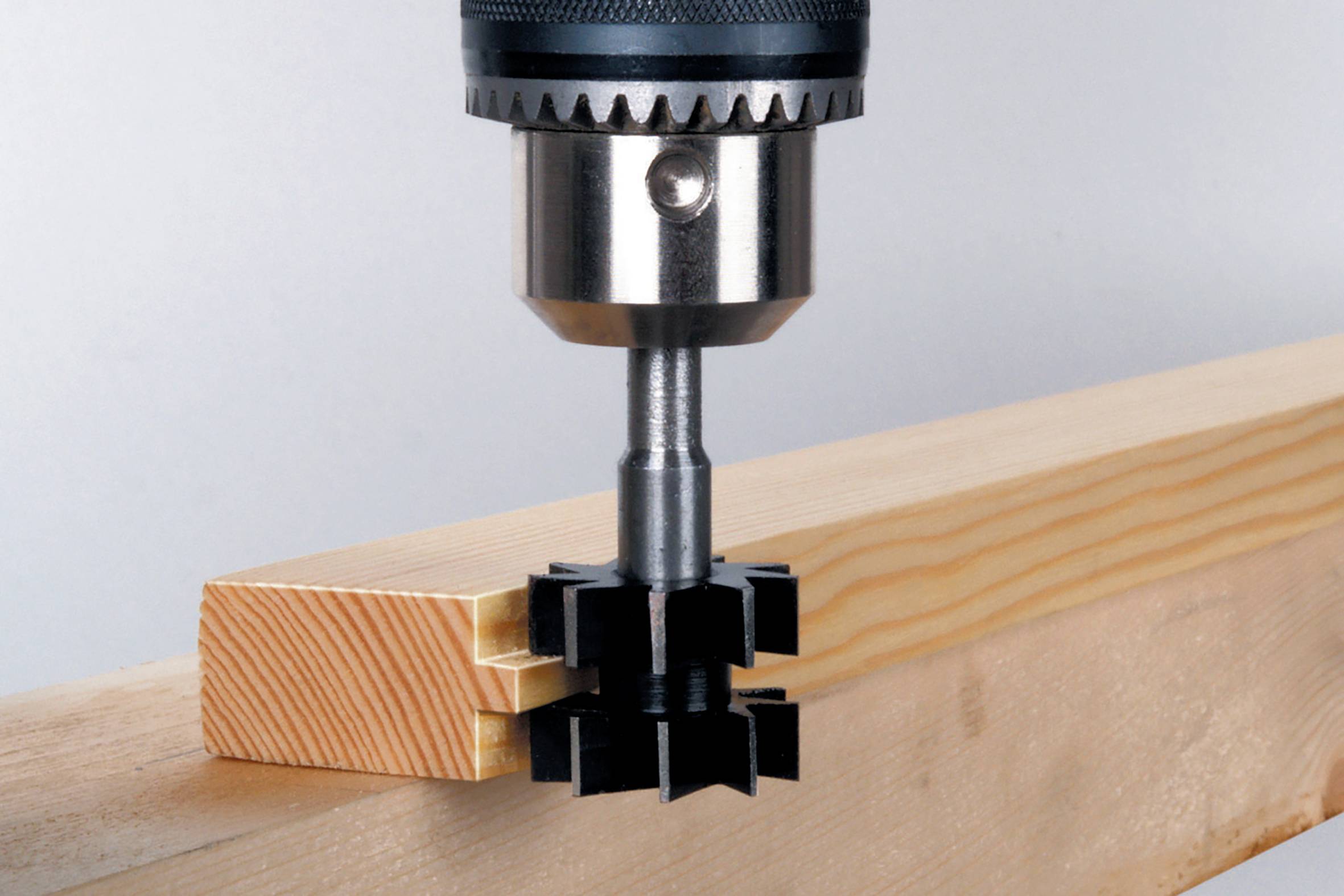 Ein Bohrer mit Fräsaufsatz bearbeitet präzise ein Holzstück, indem er eine Verzahnung fräst.
