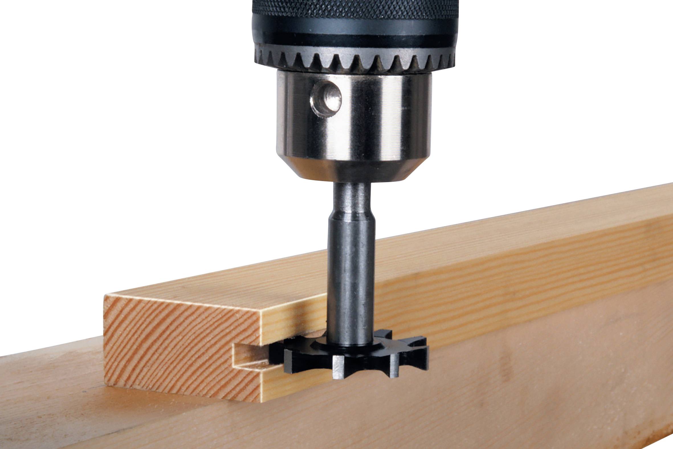 Eine Holzbearbeitungsmaschine fräst präzise eine eckige Nut in einen Holzblock, sichtbar sind Bohrer und Holz.