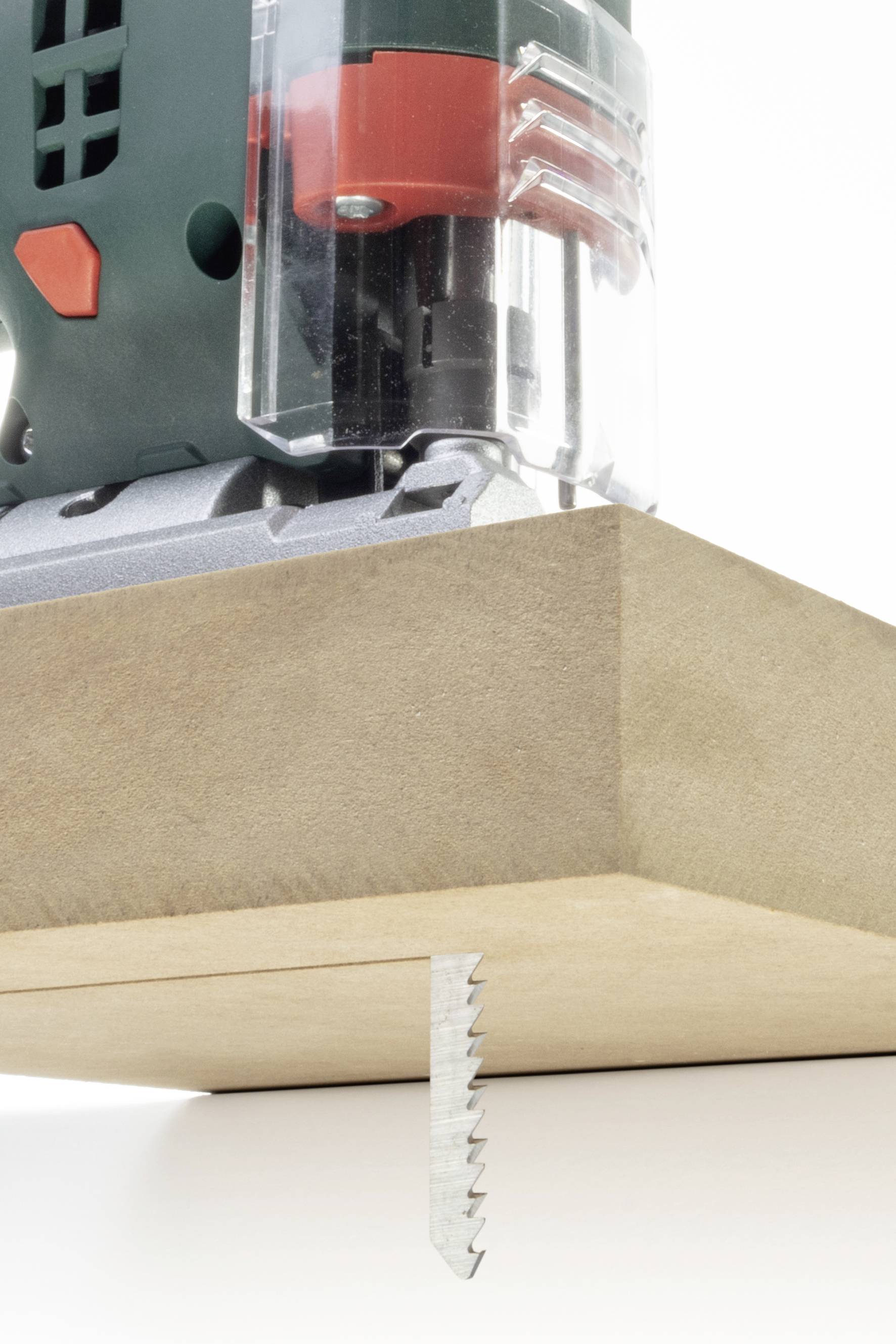 Eine Stichsäge sägt durch ein Holzbrett. Die Säge ist in Betrieb, mit einem sichtbaren gezahnten Sägeblatt.