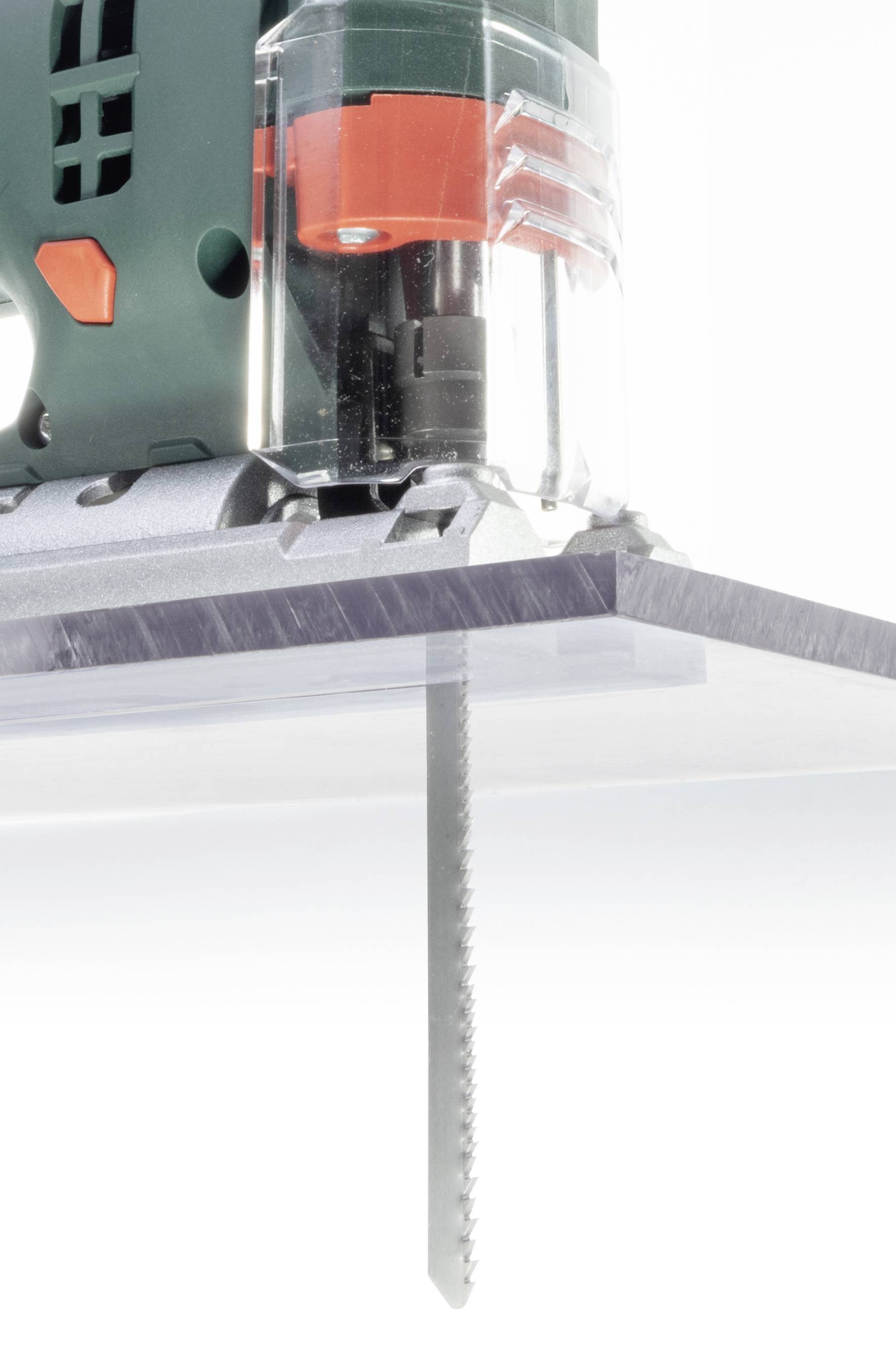 Nahaufnahme einer Stichsäge, die ein Stück Plexiglas von oben nach unten sägt. Die Sägeblätter bewegen sich durch das Material.