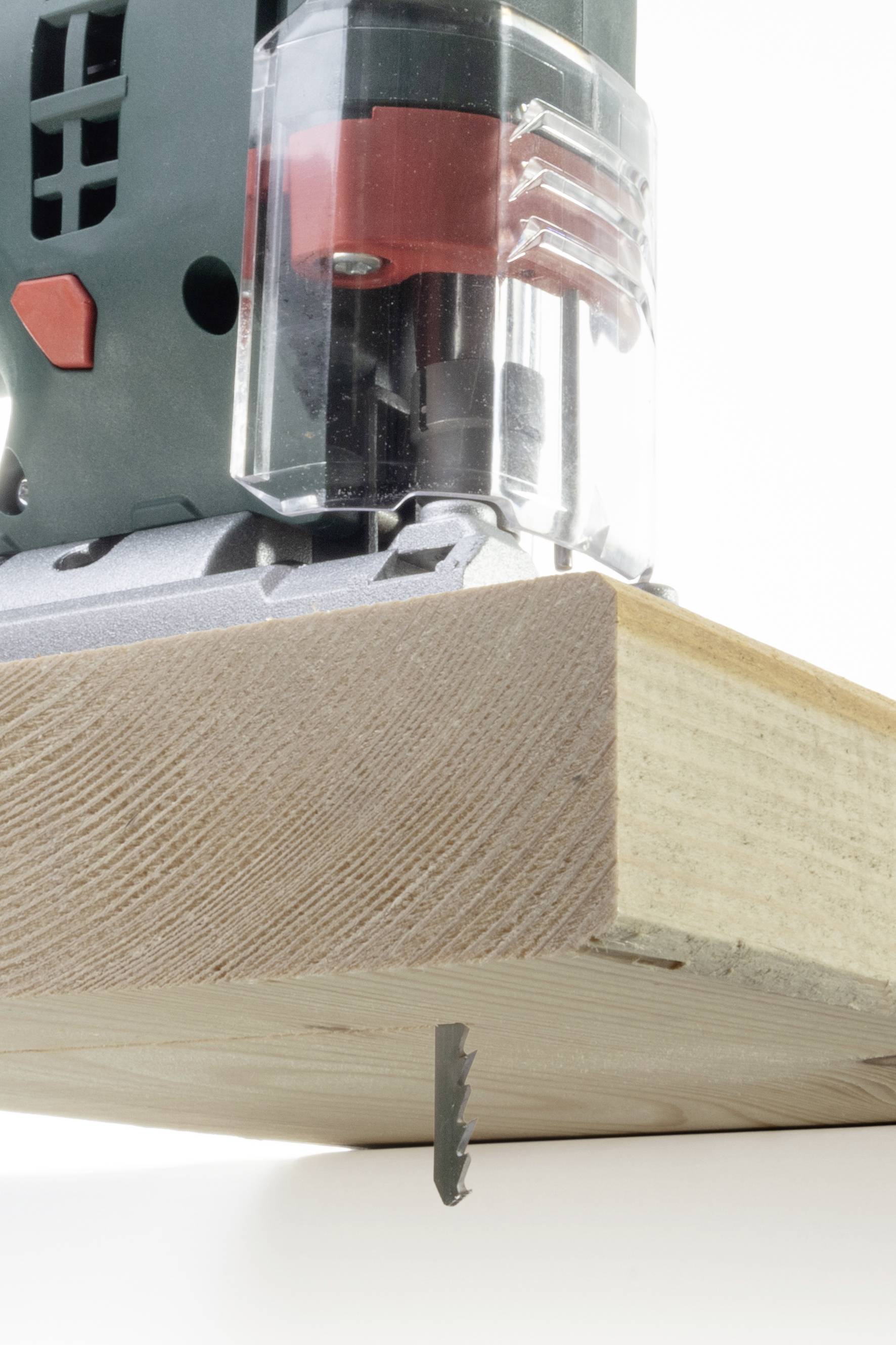 Eine Stichsäge schneidet ein Stück Holz. Das Sägeblatt ist sichtbar in Aktion, während es durch das Holz gleitet.