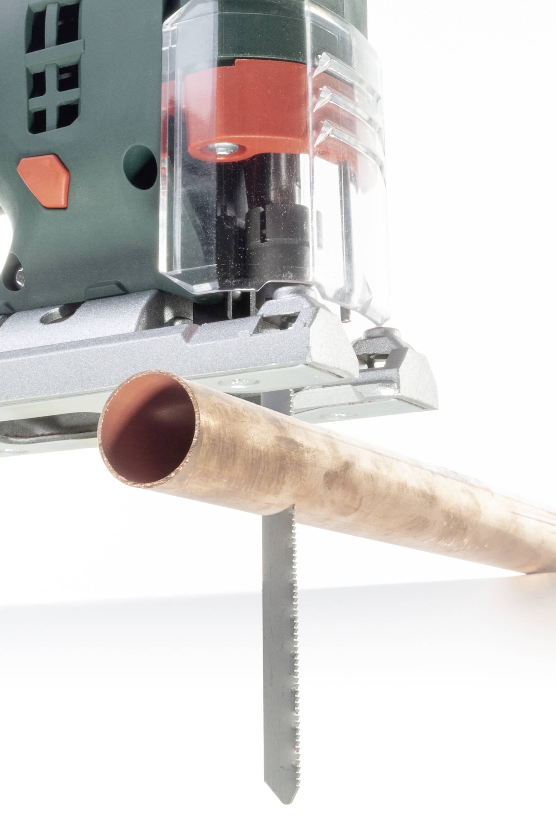 Ein Rohr wird mit einer elektrischen Stichsäge durchgeschnitten. Im Vordergrund steht die Säge, die einen präzisen Schnitt ausführt.