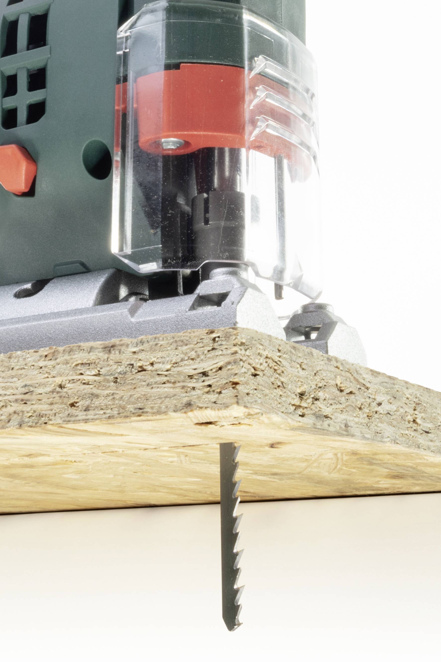 Eine elektrische Stichsäge schneidet durch eine Holzplatte. Die Säge ist teilweise sichtbar, während sie präzise durch das Material arbeitet.