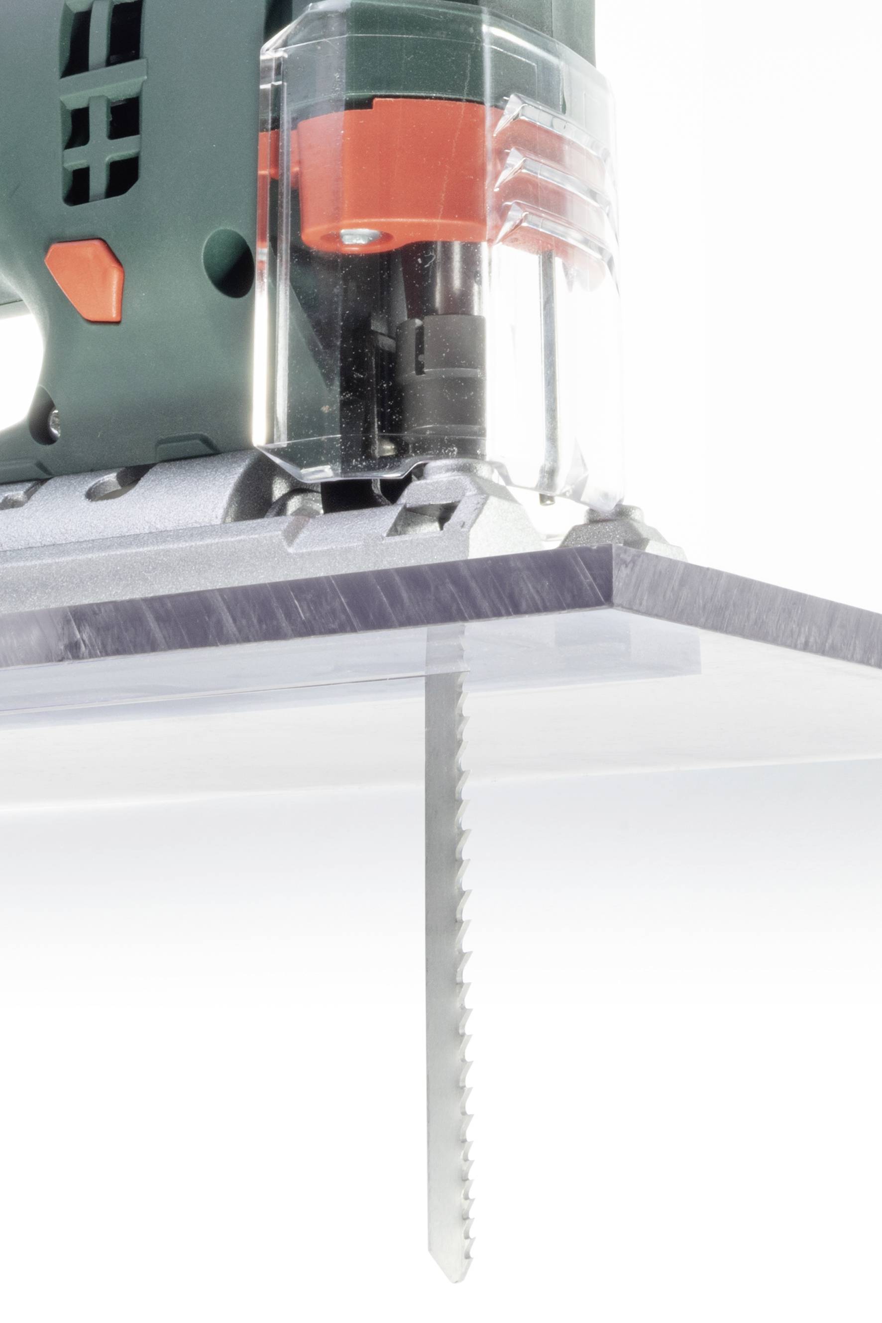 Eine Stichsäge schneidet durch eine dünne, durchsichtige Platte. Die Sägeblätter sind gezackt und das Gerät ist teilweise sichtbar.