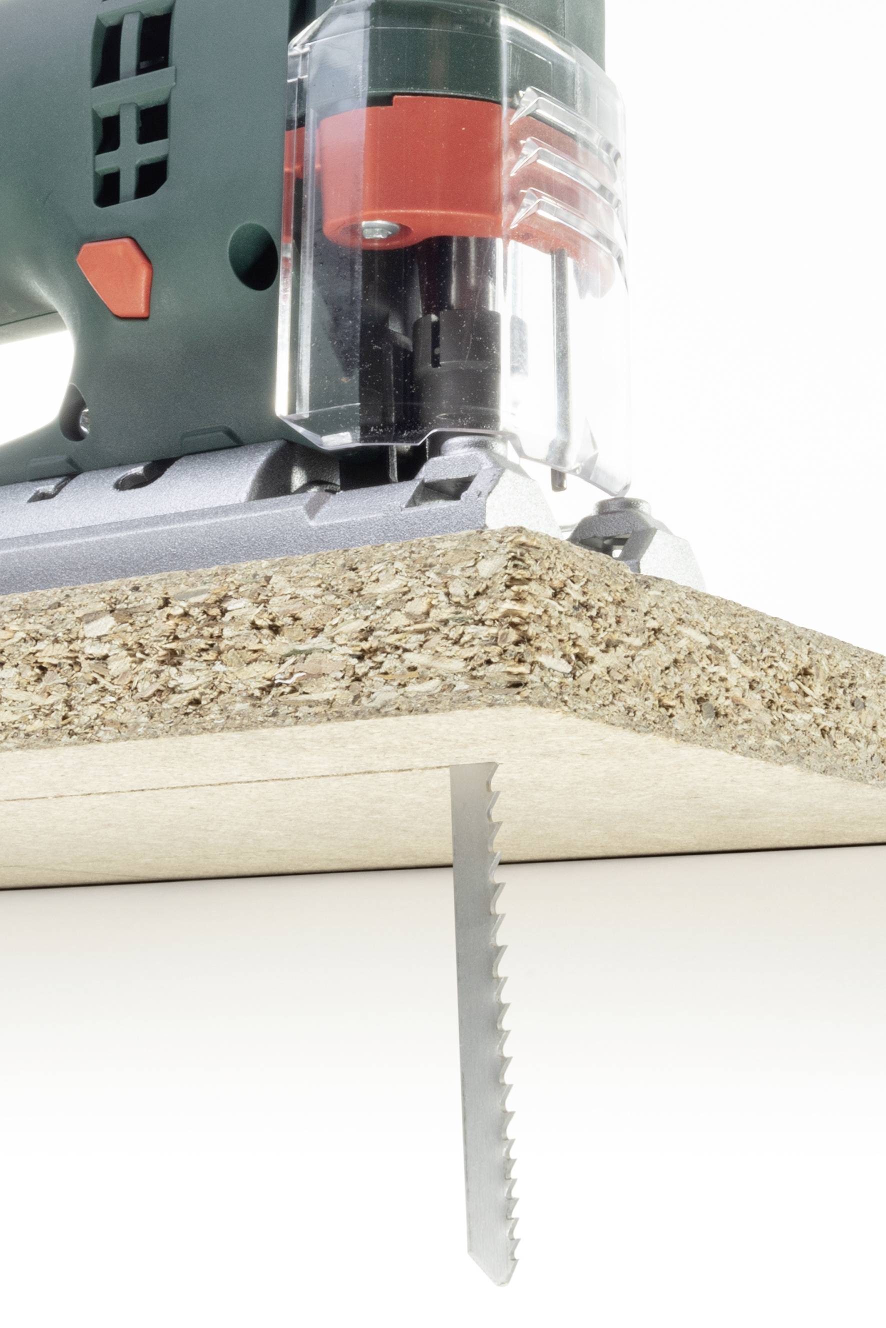 Ein elektrisches Stichsägewerkzeug schneidet präzise durch eine Spanplatte von unten.