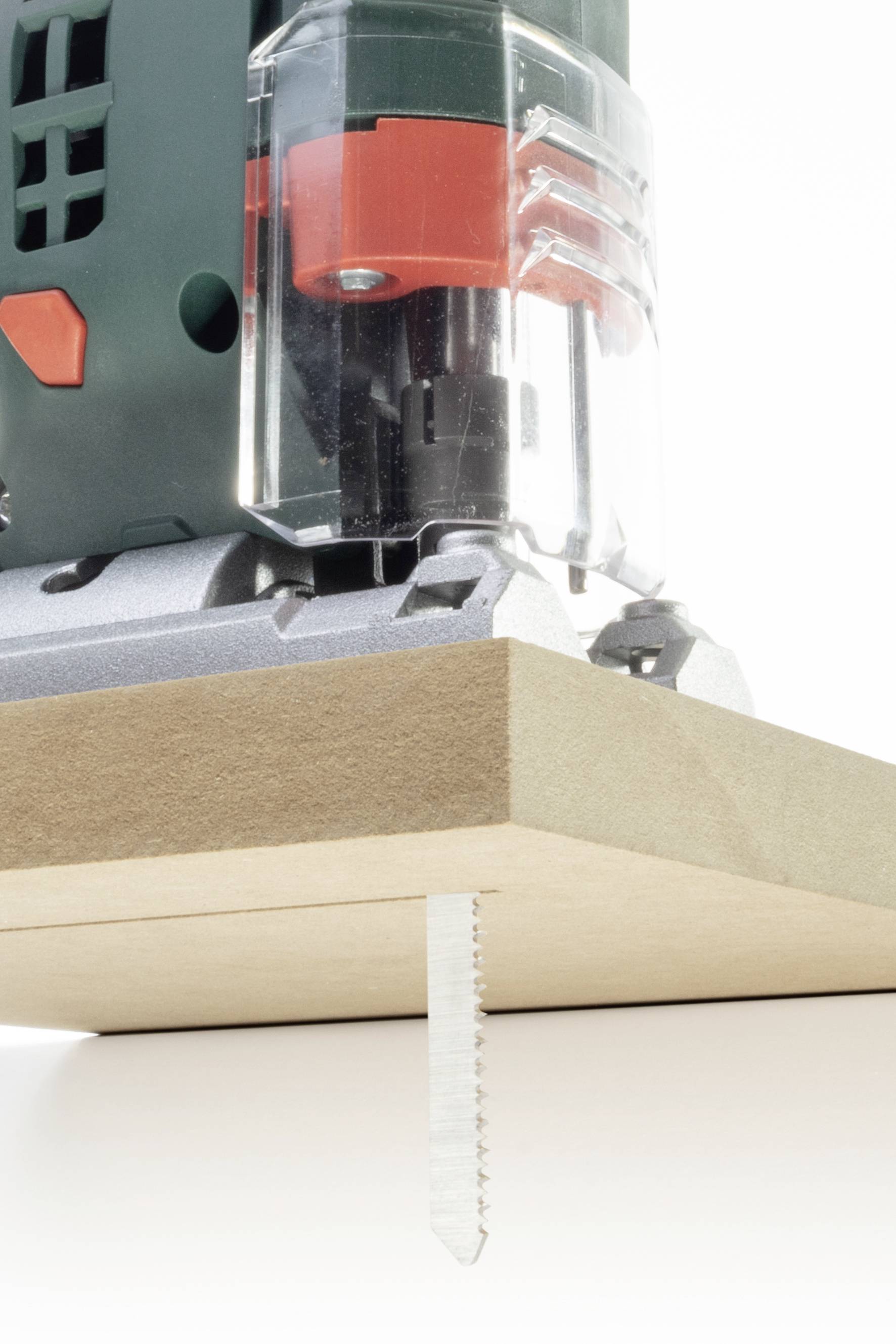 Eine Stichsäge schneidet ein Holzbrett. Die Klinge ist sichtbar unter dem Brett, während die Säge nah und detailliert gezeigt wird.