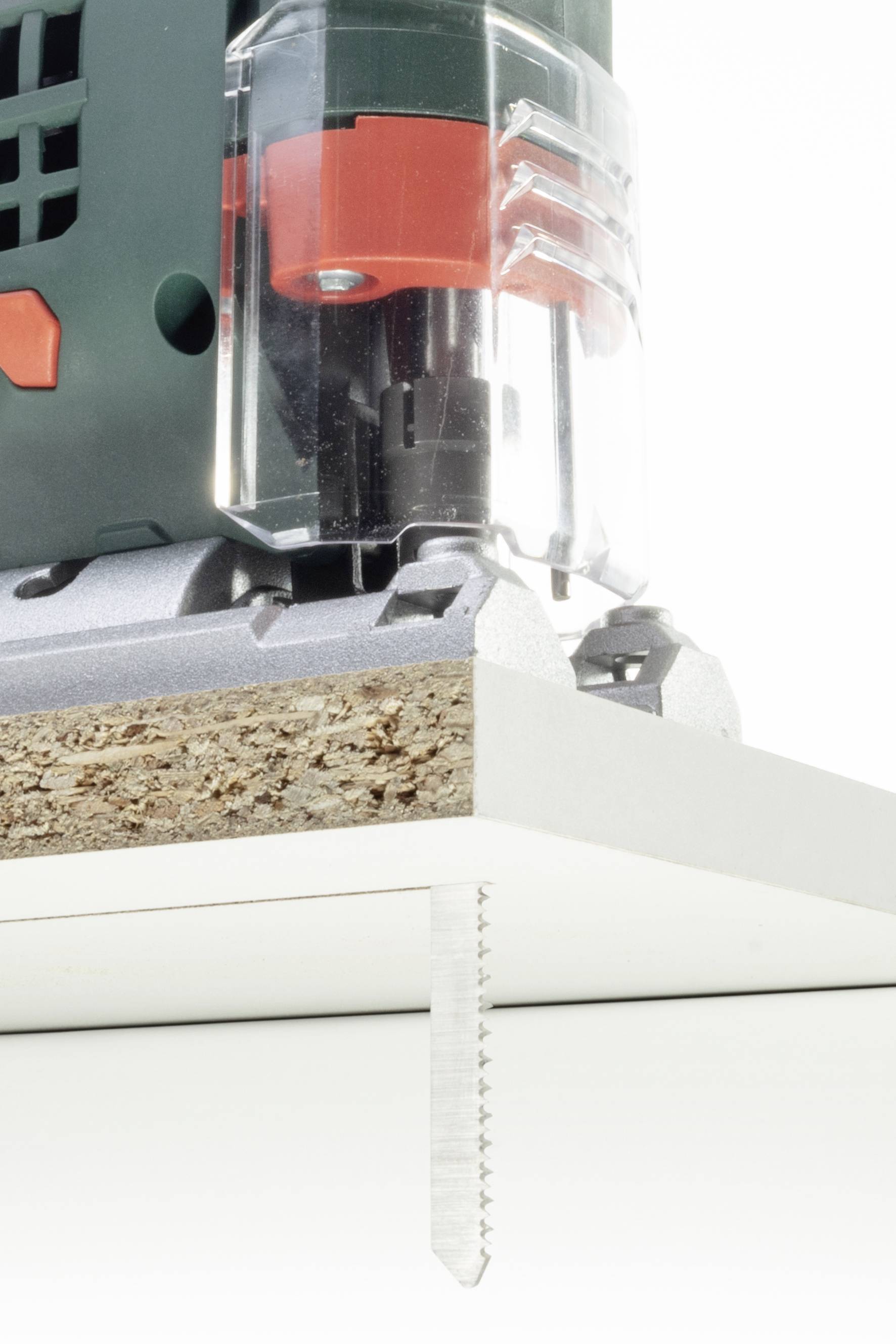 Eine elektrische Stichsäge schneidet eine Spanplatte. Die Klinge ist sichtbar in Aktion, während die Maschine das Material durchdringt.