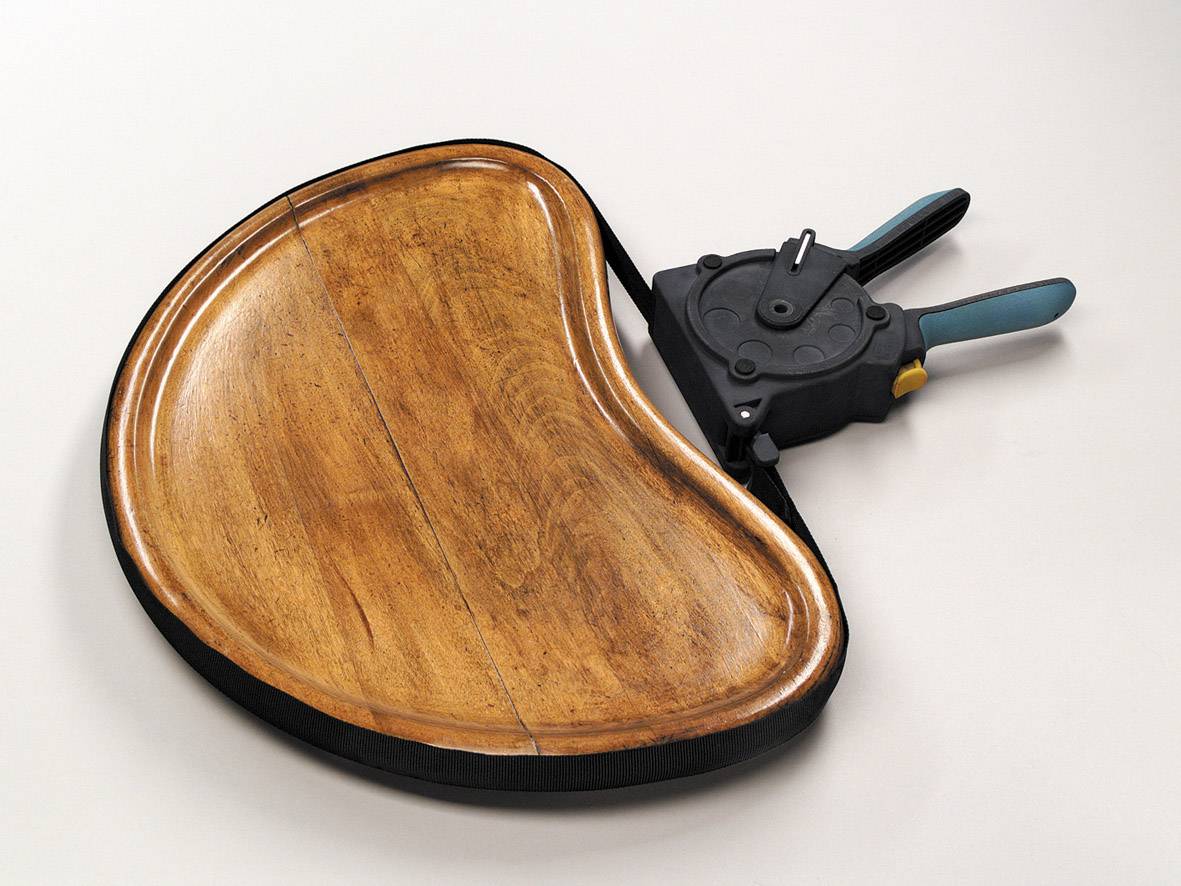 Ein hölzerner, halbmondförmiger Gegenstand mit einem schwarzen Griff und Hebel, möglicherweise ein ergonomisches Arbeitsgerät.