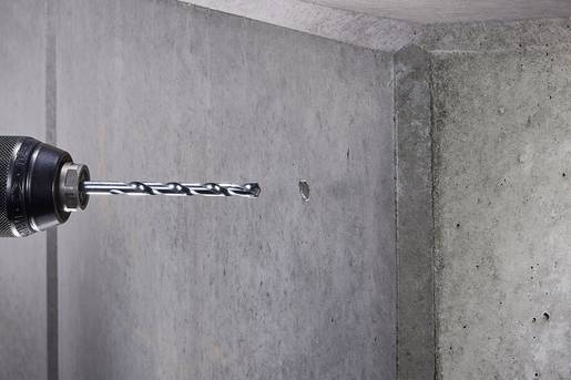 Eine Bohrmaschine bohrt ein kleines Loch in eine Betonwand.