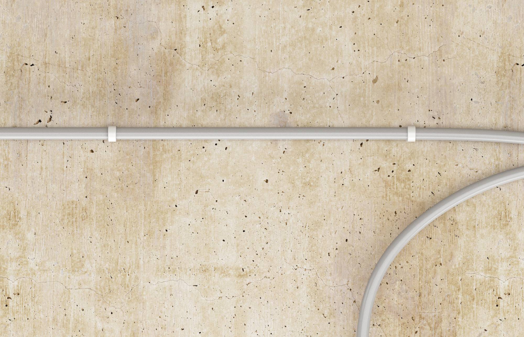 Weißes Elektrokabel verläuft horizontal über eine beige Betonwand, mit einem gekrümmten Kabelsegment, das von unten rechts eintritt.