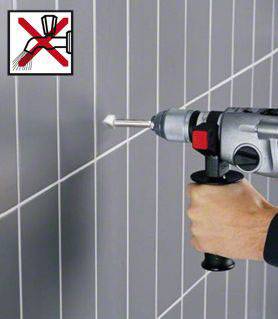 Eine Hand hält eine elektrische Bohrmaschine, die eine Fliese anbohrt. Ein Symbol zeigt 'Kein Hammer' über einem Bild von Fliesen.