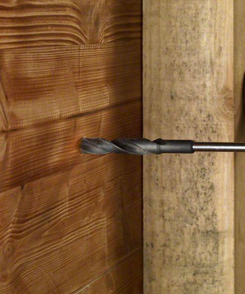 Ein Bohrer in Aktion, der ein Loch in eine Holzwand bohrt. Die Holzmaserung ist deutlich sichtbar.