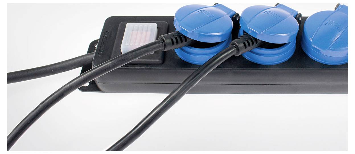 Eine schwarze Steckdosenleiste mit drei angeschlossenen blauen Schutzkontaktsteckdosen und zwei eingesteckten Stromkabeln.