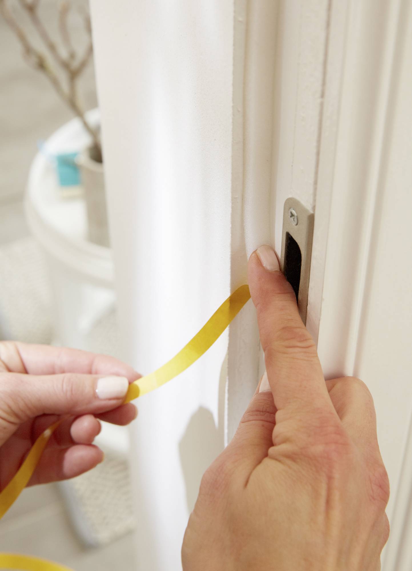 Eine Person bringt ein gelbes Dichtungsband an der Türrahmenkante an, um Zugluft zu verhindern und Energieeffizienz zu verbessern.