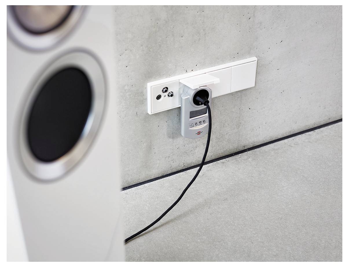Elektrofahrzeug-Ladestecker, der an eine Wandsteckdose neben einem Autoreifen an einer Betonwand angeschlossen ist.