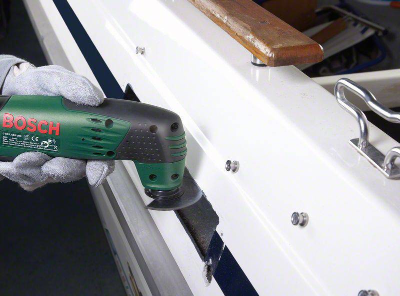 Eine Person schleift mit einem grünen Elektrowerkzeug eine Oberfläche an einem Boot. Links ist das Bosch-Logo auf dem Gerät sichtbar.