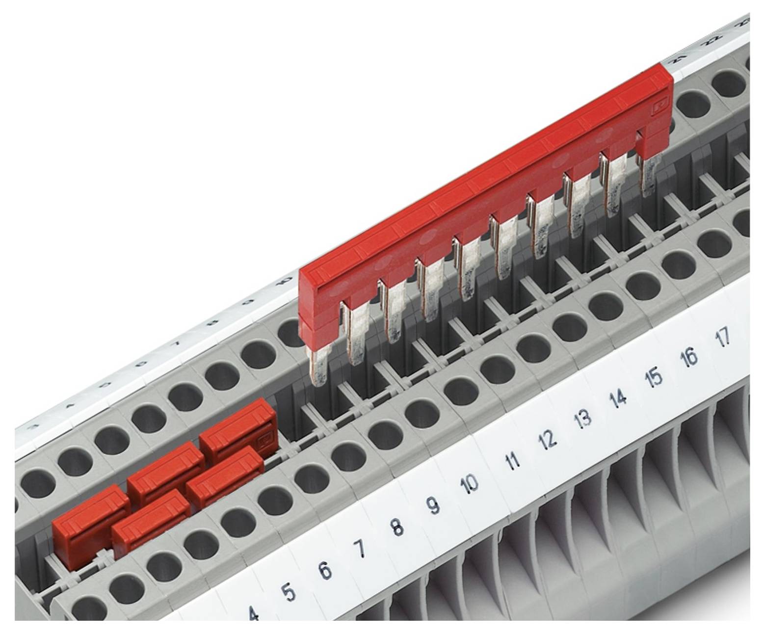 Zwei Reihen von elektrischen Klemmenblöcken mit nummerierten Anschlüssen; ein roter Stecker verbindet mehrere Anschlüsse in der oberen Reihe.