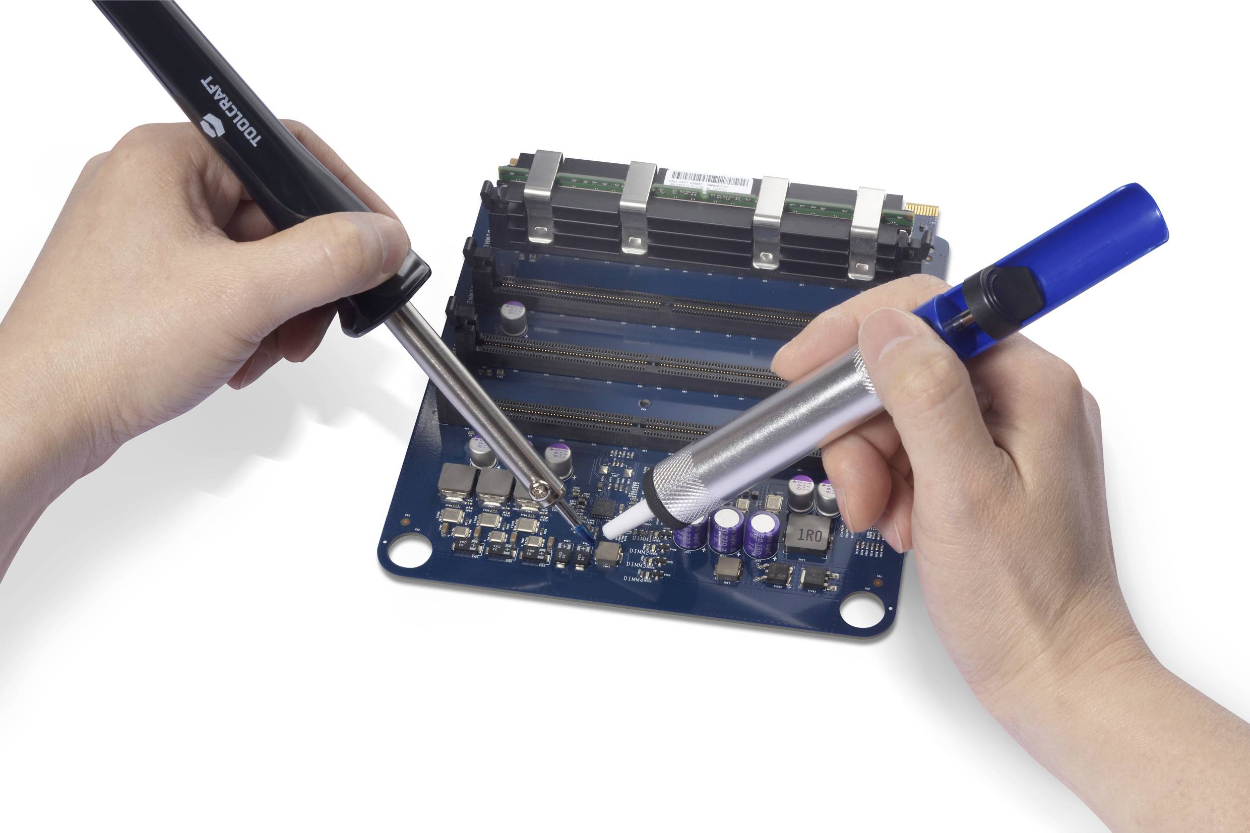 Zwei Hände arbeiten mit Lötkolben und Entlötsauger an einer blauen Leiterplatte. Sichtbar sind verschiedene elektronische Bauteile.