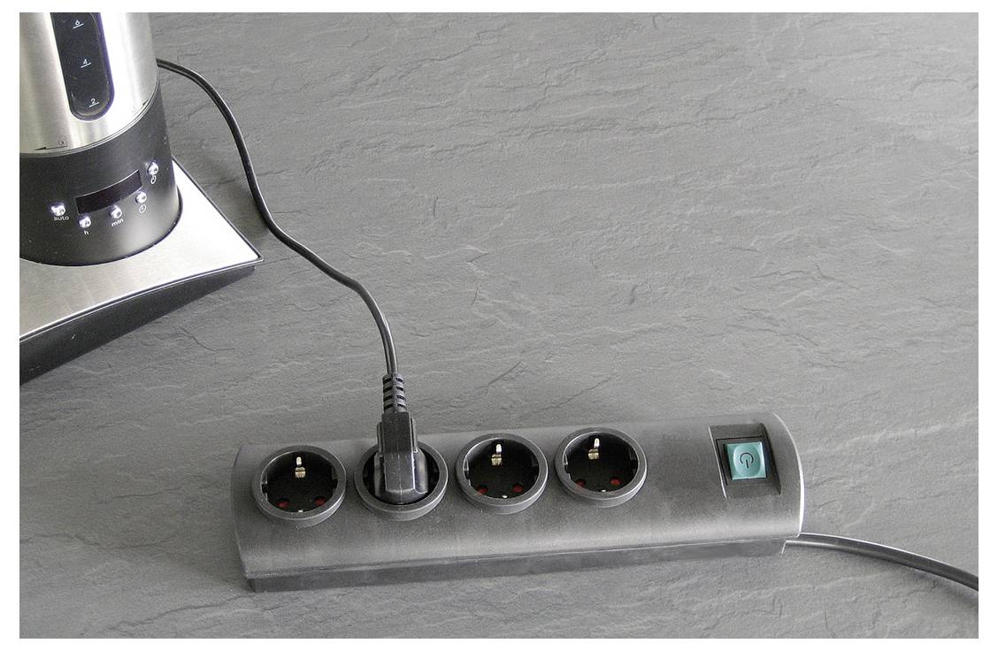 Steckerleiste mit vier runden Steckdosen und einem petrolblauen Ein-/Ausschalter, mit einem eingesteckten Stecker und einer Wasserkocher-Basis in der Nähe.