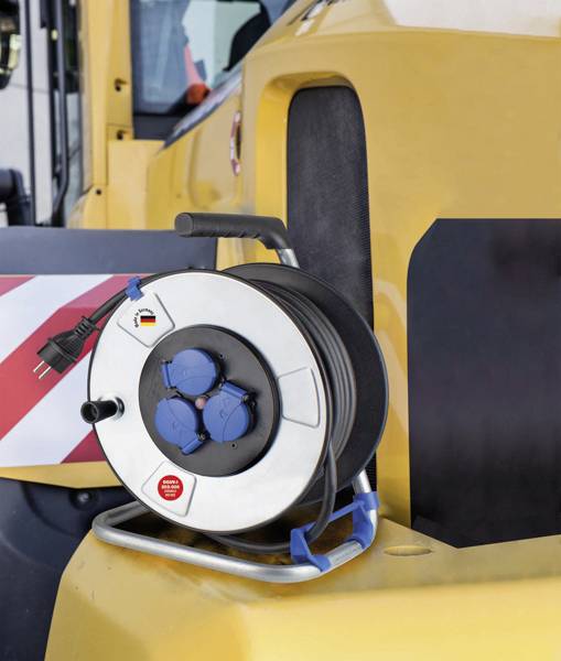 Eine Kabeltrommel mit mehreren Steckdosen und einem Kabel, platziert auf einem gelben Baufahrzeug, vermutlich für Baustellen-Einsatz.