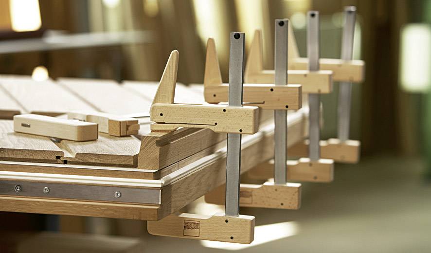 Mehrere Holzklemmen halten Holzstücke auf einer Werkbank zusammen, um präzises Arbeiten in einer Holzwerkstatt zu ermöglichen.