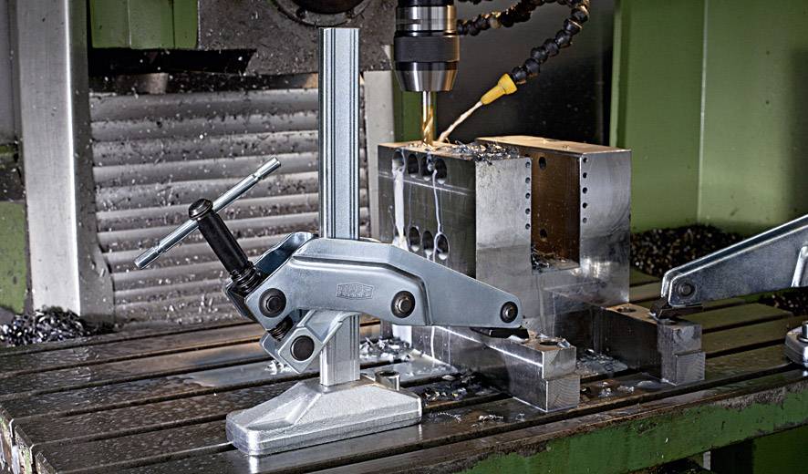 Eine CNC-Maschine bohrt präzise in einen Metallblock, der von einer Halterung fixiert wird. Metallspäne liegen verstreut auf der Arbeitsfläche.