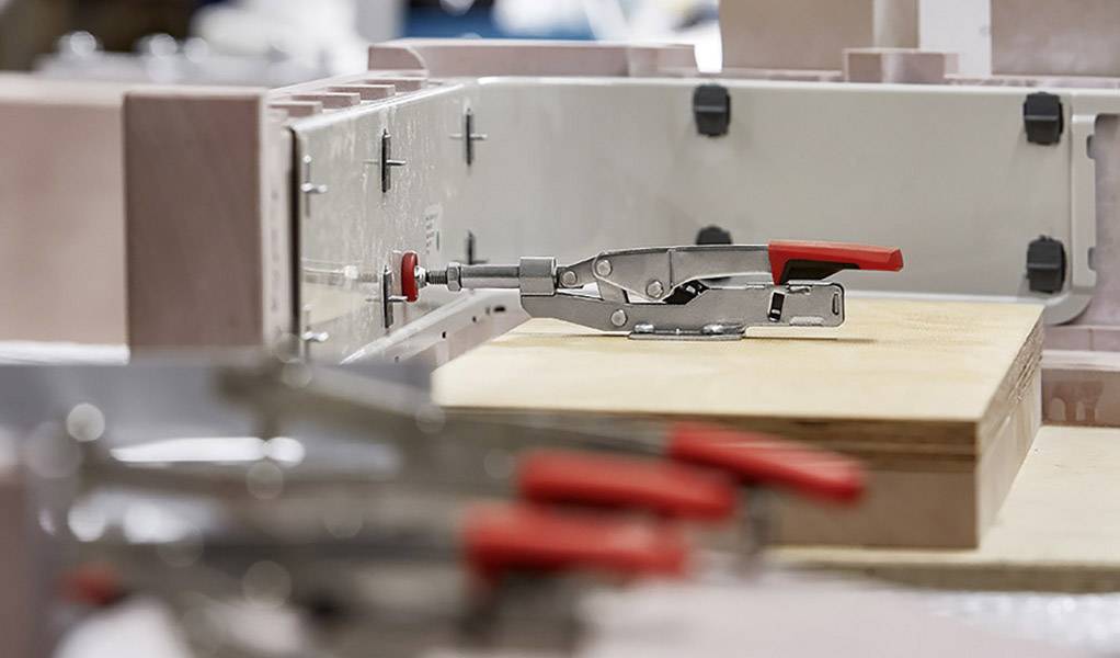 Metallische Klammern halten ein Holzbrett in einem industriellen Umfeld.