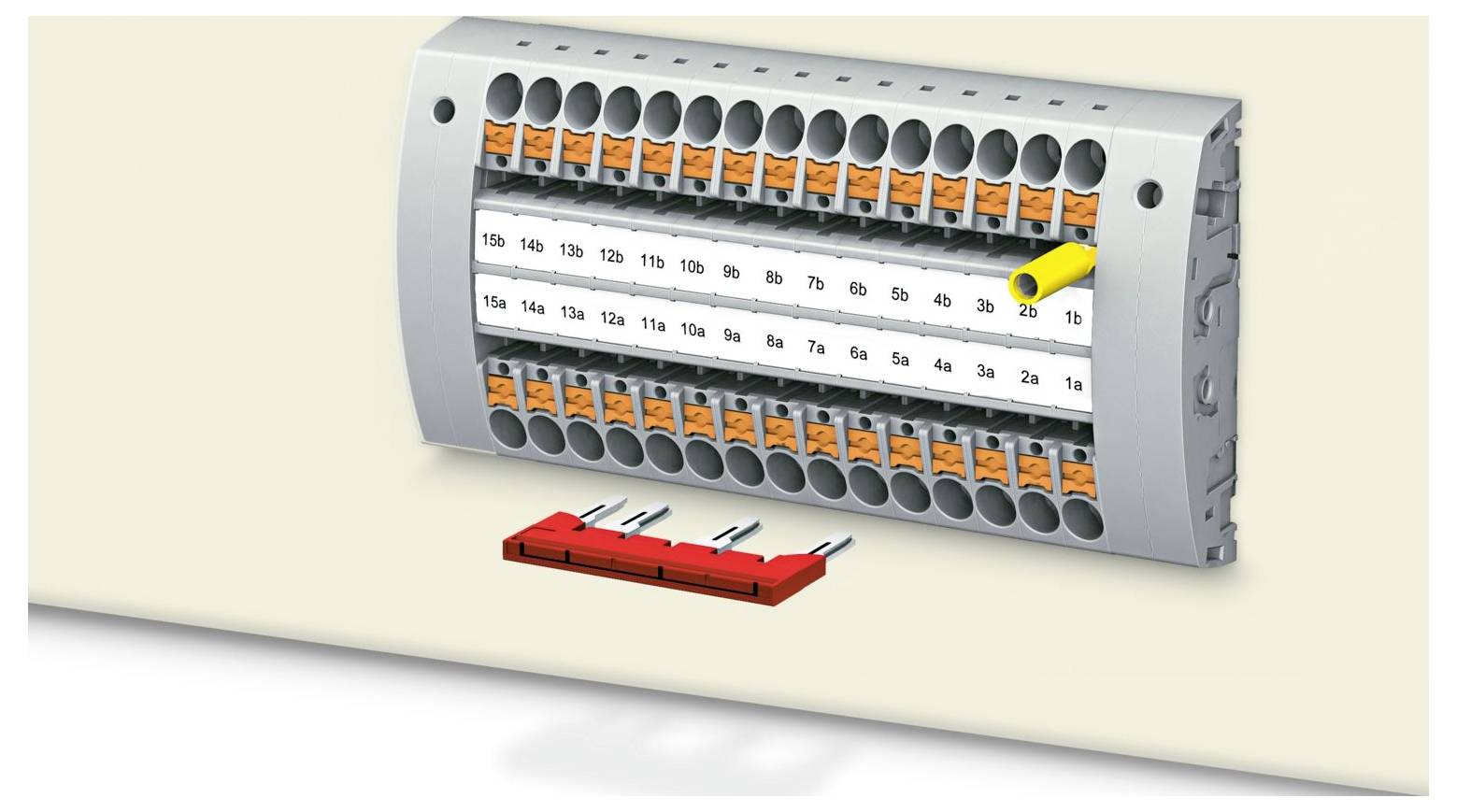 Ein elektrischer Stecker mit mehreren beschrifteten Anschlüssen, in den ein einzelnes gelbes Modul eingesteckt ist. Darunter ein rotes Teil mit mehreren Metallkontakten.