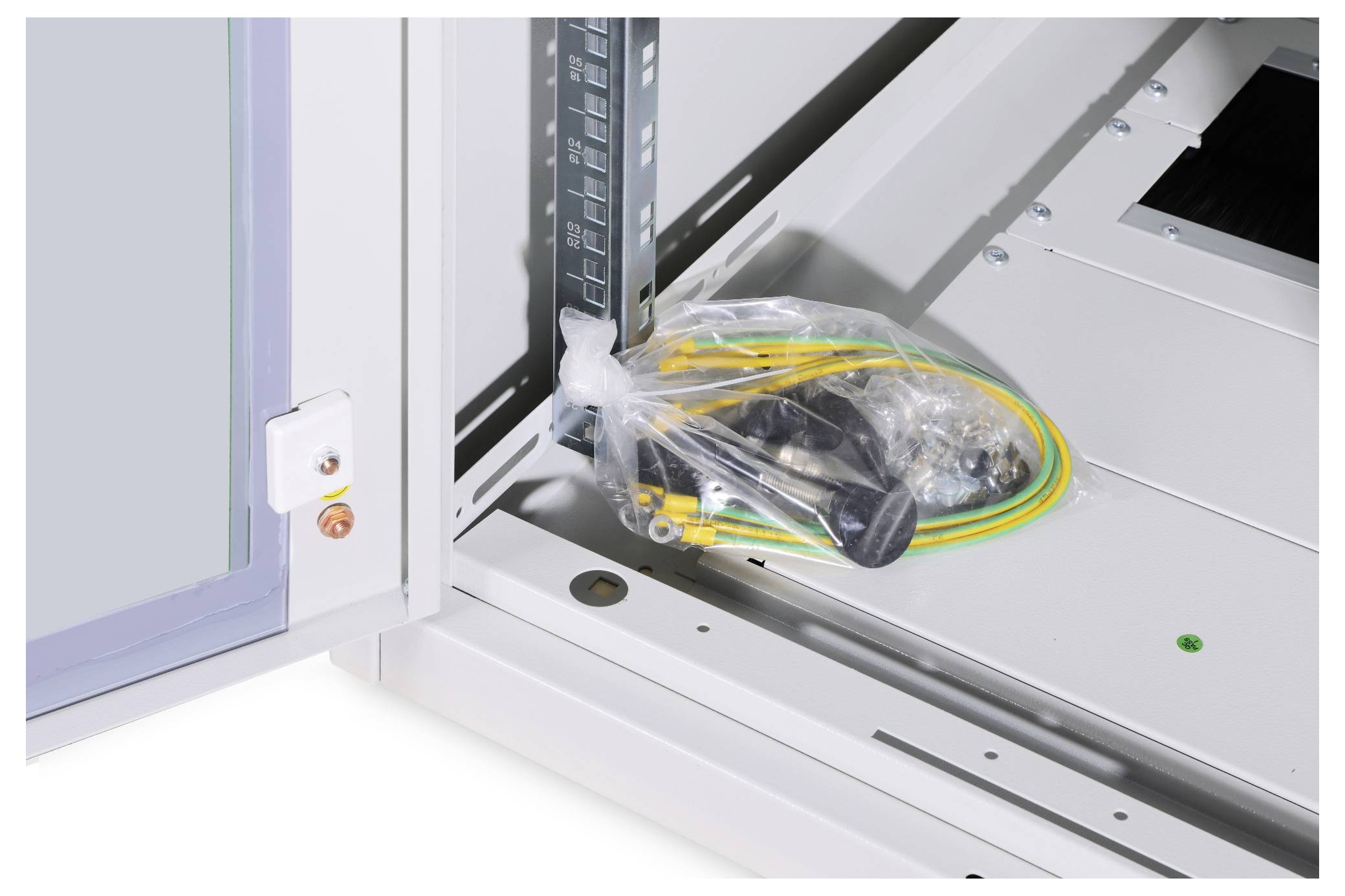 Plastiktüte mit Kabeln und Montagezubehör liegt in geöffnetem elektronischem Schaltschrank.