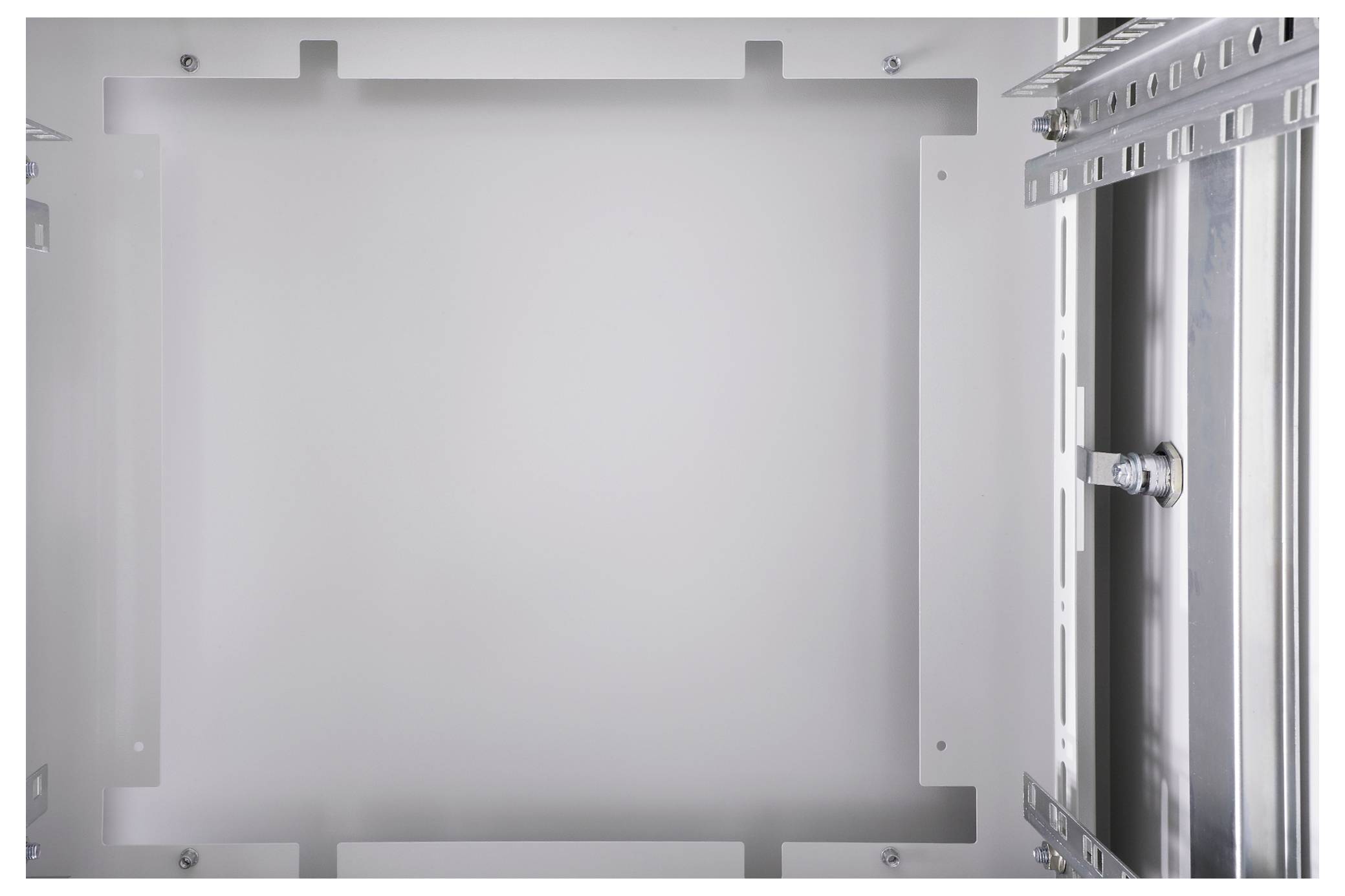 Ein leerer Metall-Schaltschrank, beleuchtet, mit sichtbaren Montageplatten und Halterungen an den Rändern.