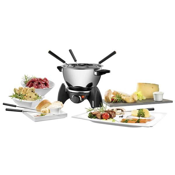 Ein Fondue-Set mit Topf und vier Gabeln, umgeben von Platten mit Fleisch, Brot, Käse und Gemüse. Perfekt für ein geselliges Essen.